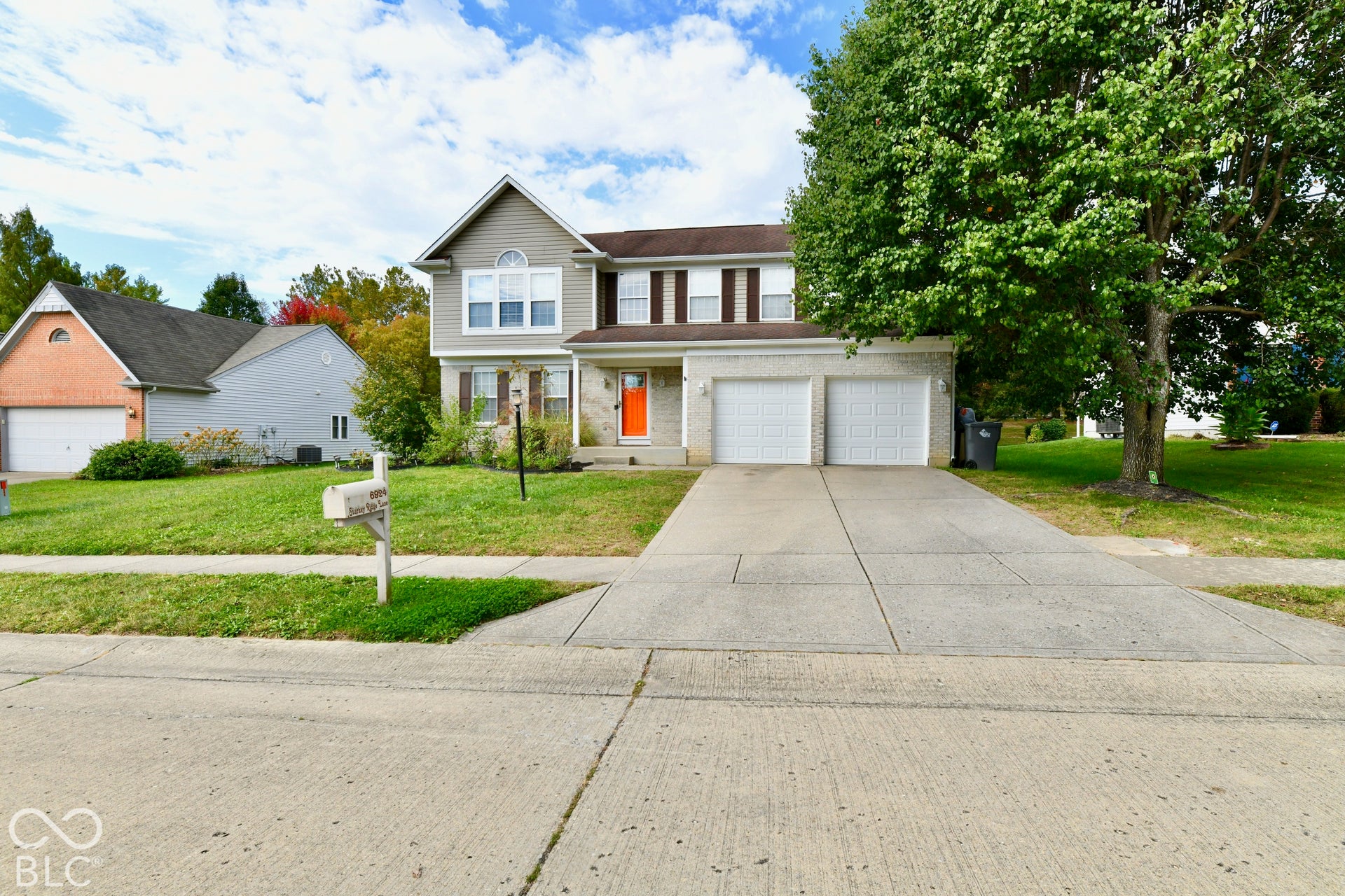 Two-story residence featuring a mixed brick and horizontal siding facade, attached two-car garage, concrete driveway, and front lawn