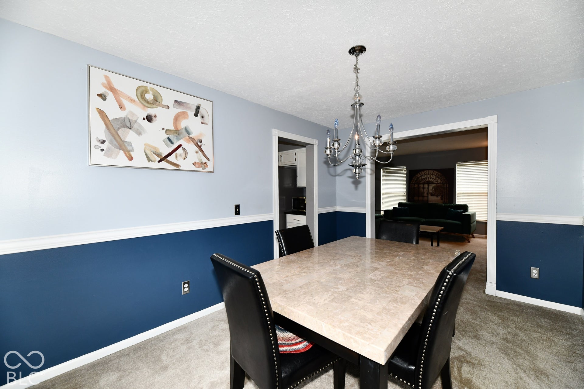 Dining area featuring dual-tone wall paint, waist-high chair rail molding, and a multi-arm decorative chandelier