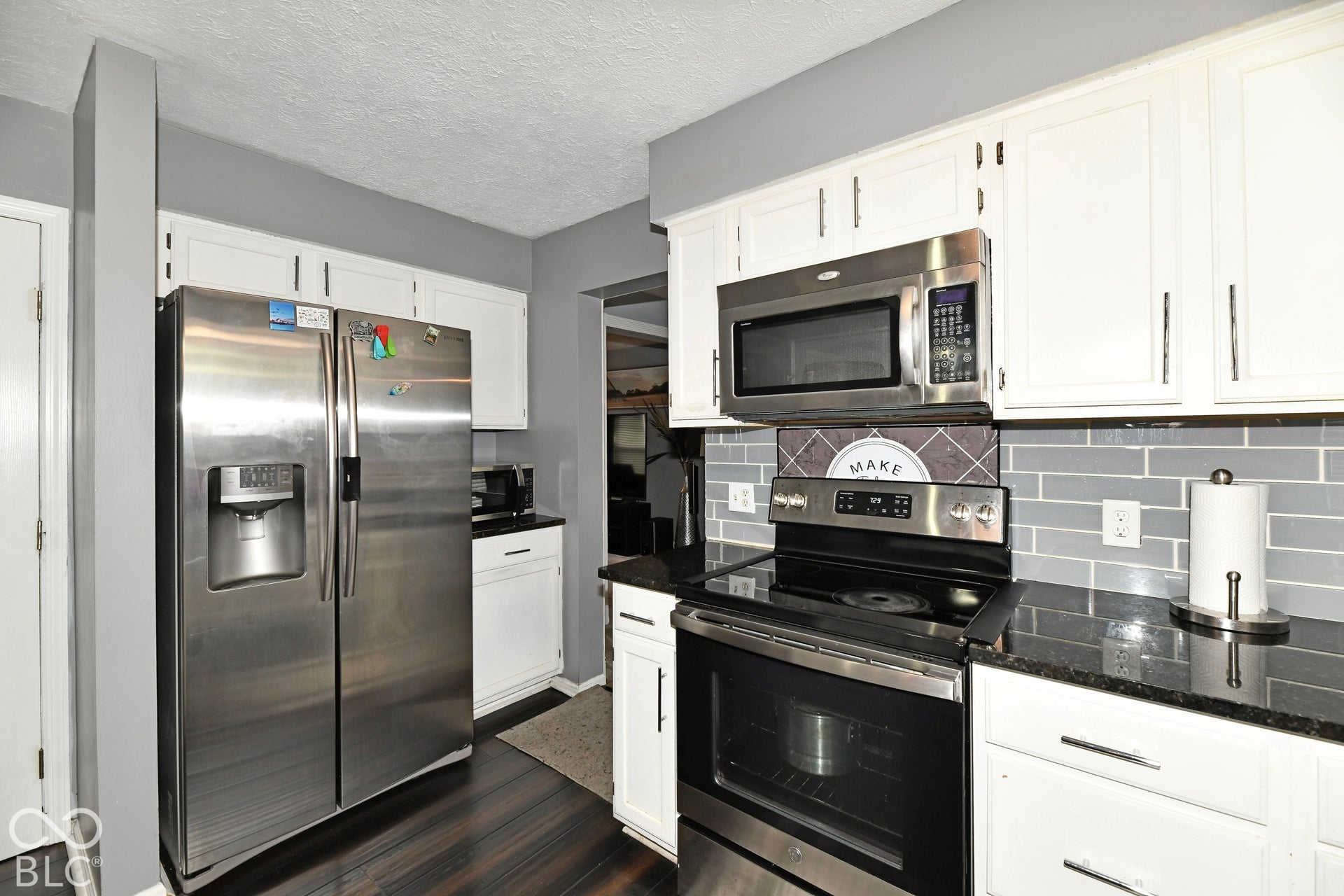Kitchen featuring white cabinetry, dark stone-finish countertops, stainless steel appliances, and a grey subway tile backsplash
