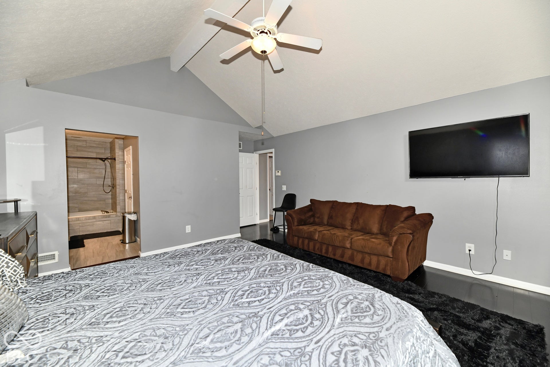 Vaulted ceiling with white central ceiling fan and dark-finish flooring