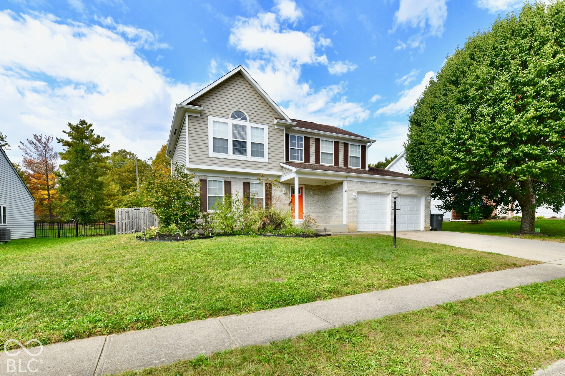 Two-story exterior featuring light-toned masonry and horizontal siding, double-car garage, and a covered front entry