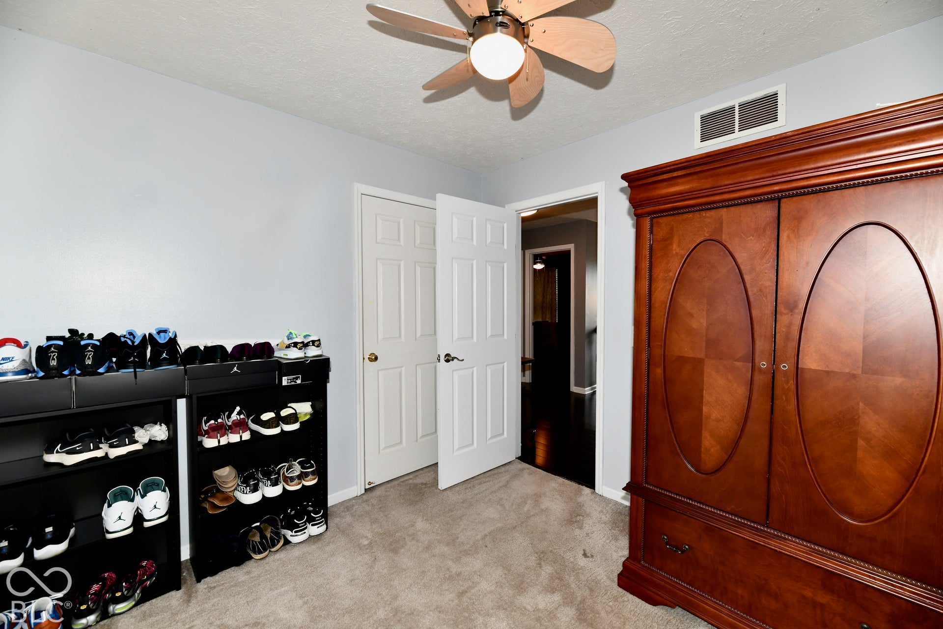 Interior space featuring neutral wall paint, carpeted flooring, a multi-blade ceiling fan with integrated lighting, and a six-panel interior door