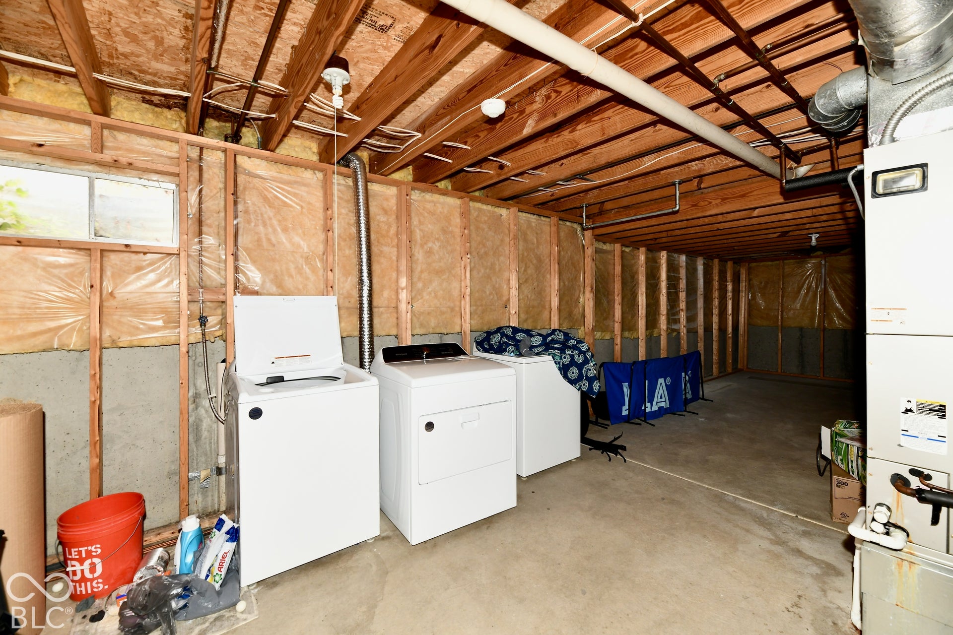 Unfinished lower level featuring exposed wood joists, concrete flooring, exterior-grade wall insulation, and a mechanical furnace system