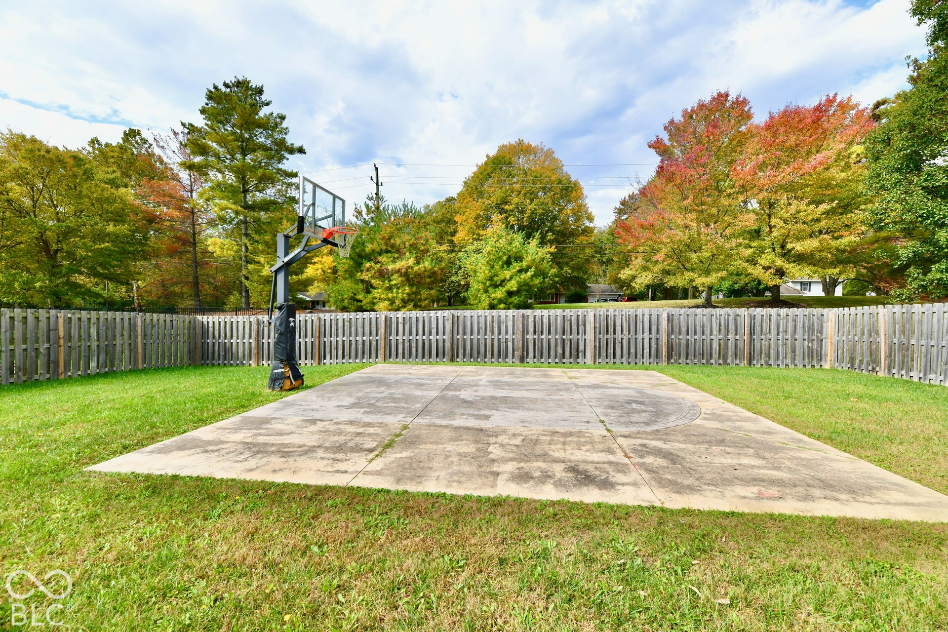 Backyard featuring a concrete basketball court, integrated hoop system, and wood-slat privacy fencing