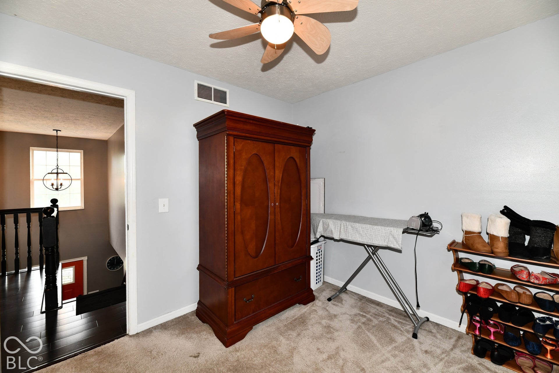 Room interior featuring neutral wall paint, carpeted flooring, and a ceiling-mounted light fixture with a multi-blade fan