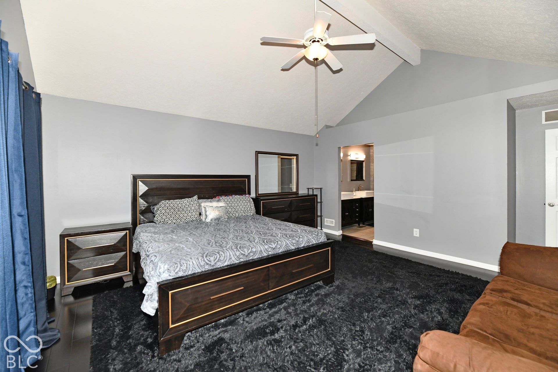 Vaulted ceilings featuring a central white ceiling fan, dark wood-finish flooring, and a neutral wall color palette