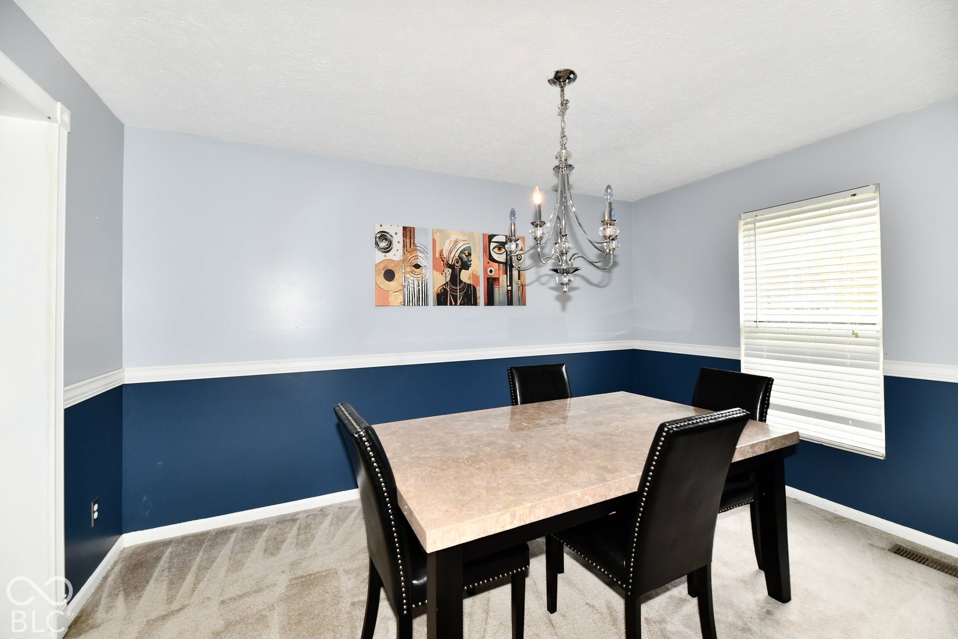 Dining area featuring two-tone wall paint, a chair rail, a multi-arm metal chandelier, and a horizontal window with blinds