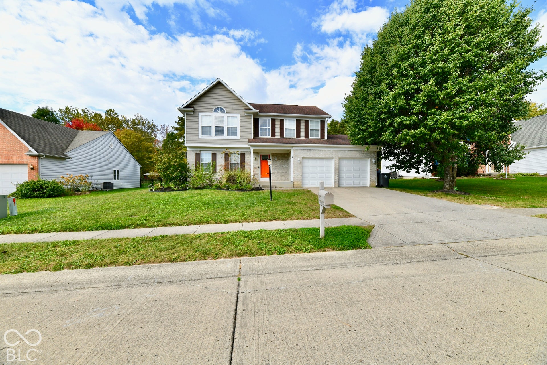 Two-story residence featuring a combination of light-colored siding and stone veneer, a dual-car garage, and a concrete driveway