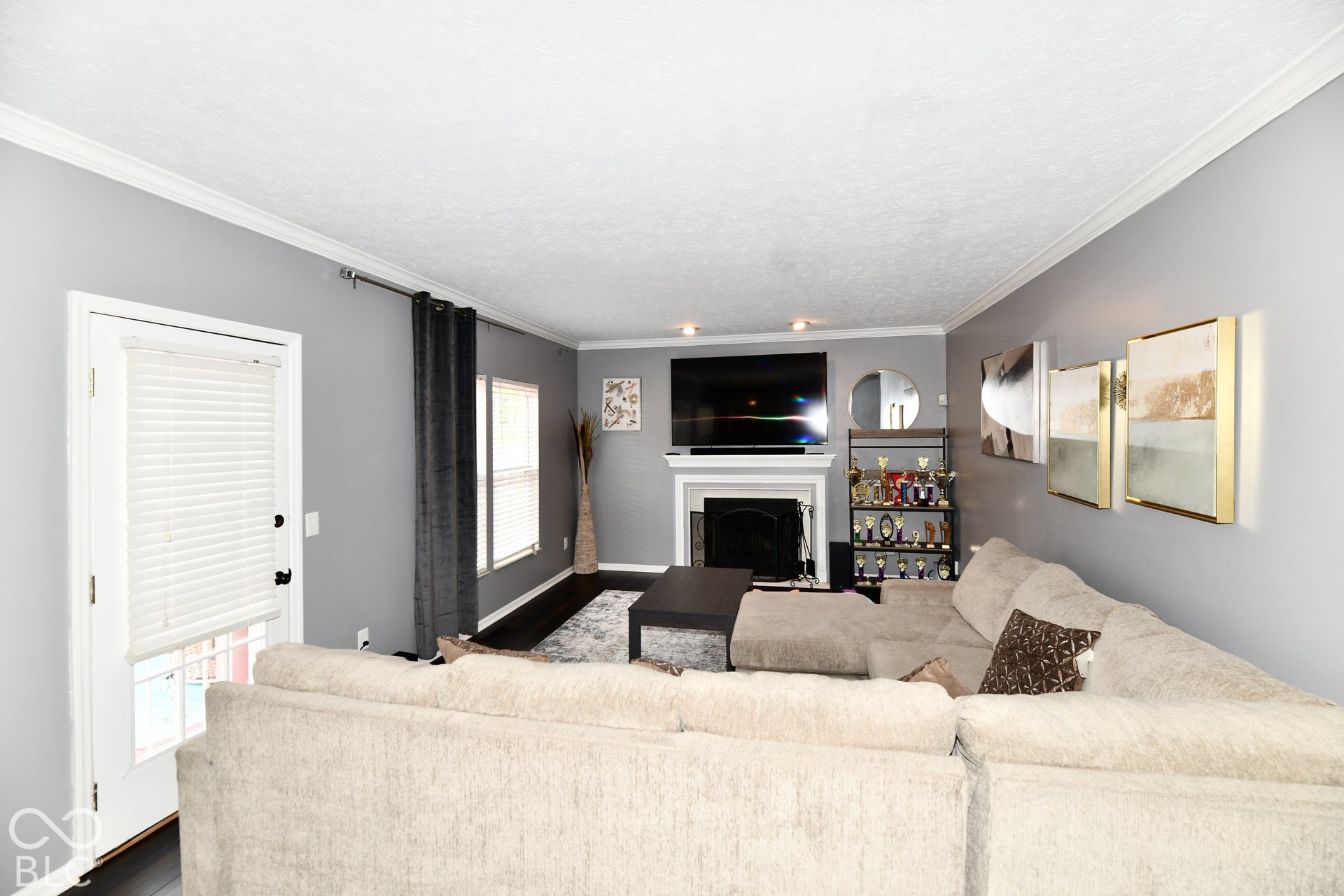 Living area featuring dark wood-finish flooring, a wood-burning fireplace with a mantel, crown molding, and recessed lighting