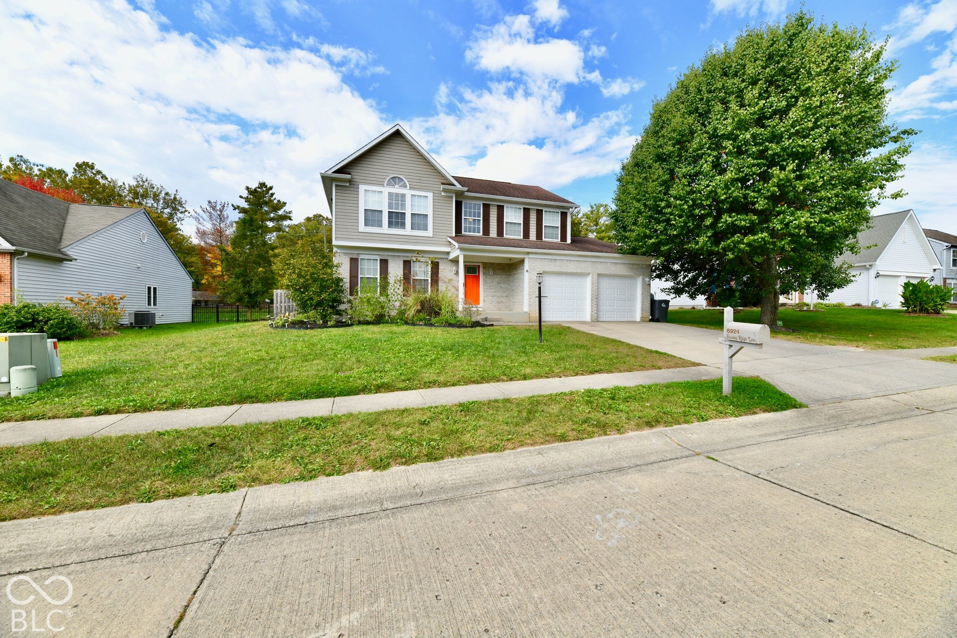 Two-story residence featuring light-toned masonry, vinyl siding, a multi-paneled front door, an attached two-car garage, and concrete driveway