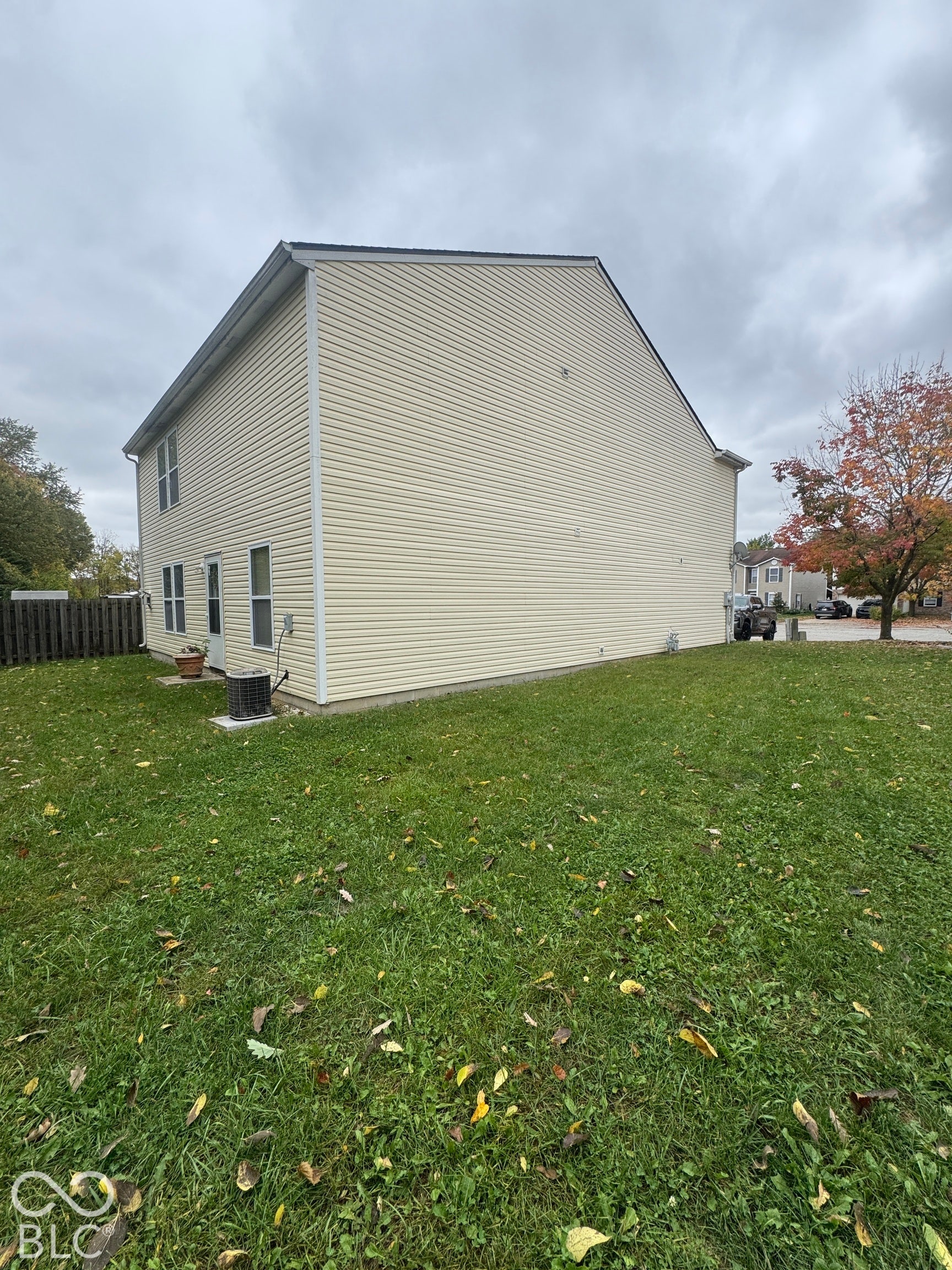 Two-story exterior featuring light-colored horizontal siding, multiple windows, and a dedicated outdoor lawn area