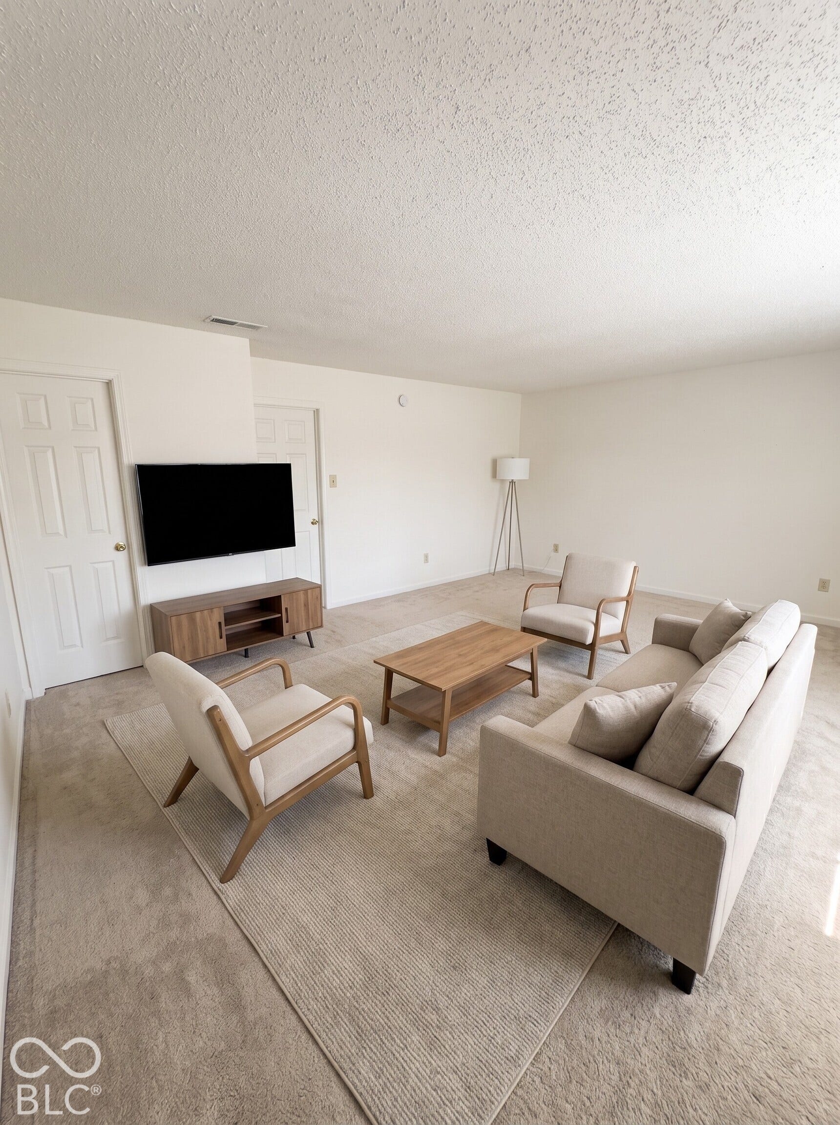 Virtually Altered - Neutral interior space featuring textured ceiling, carpeted flooring, and two interior doors with six-panel detailing