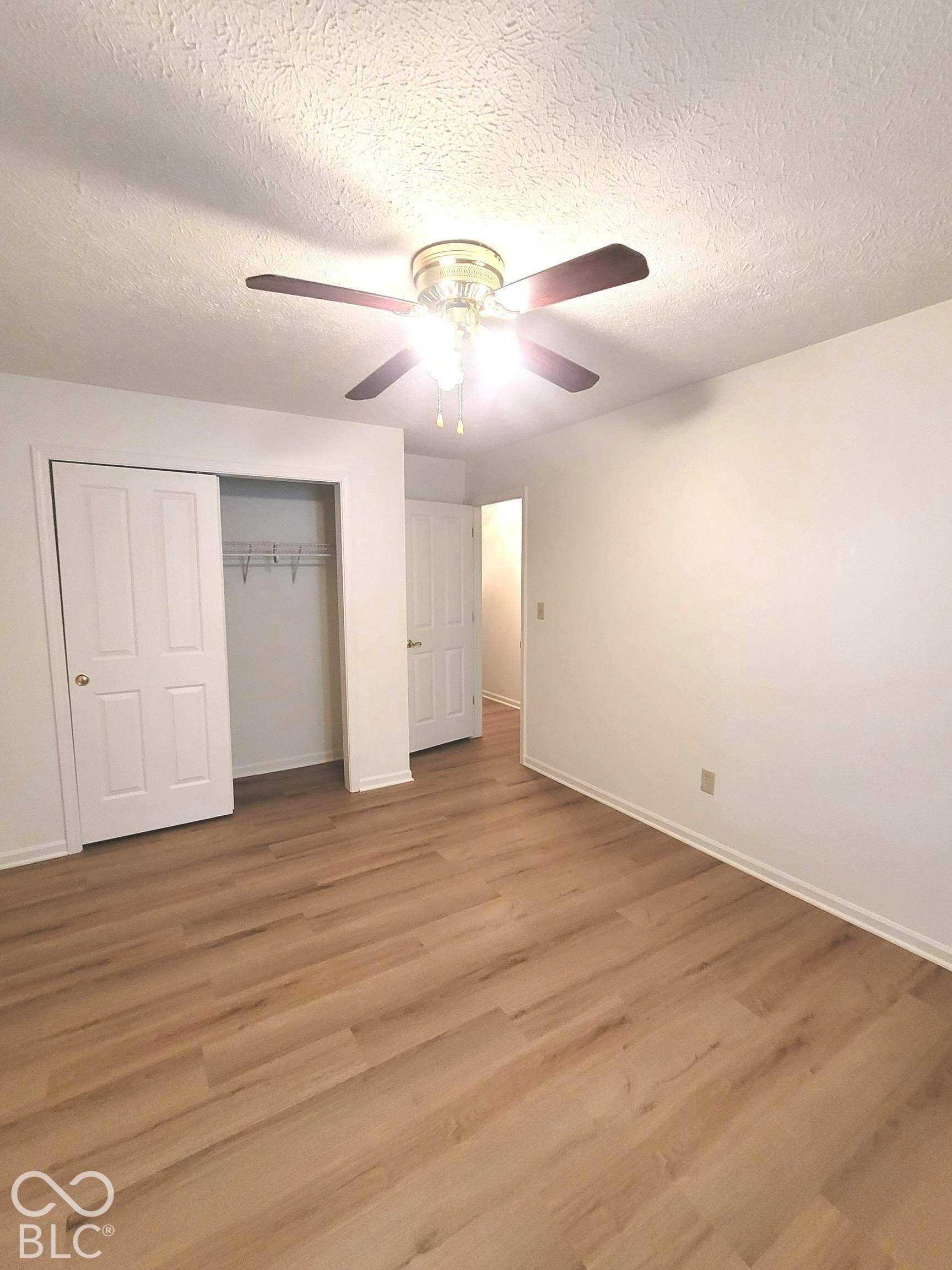 Virtually Altered - Room featuring wood-finish flooring, a ceiling fan with integrated lighting, and white six-panel doors
