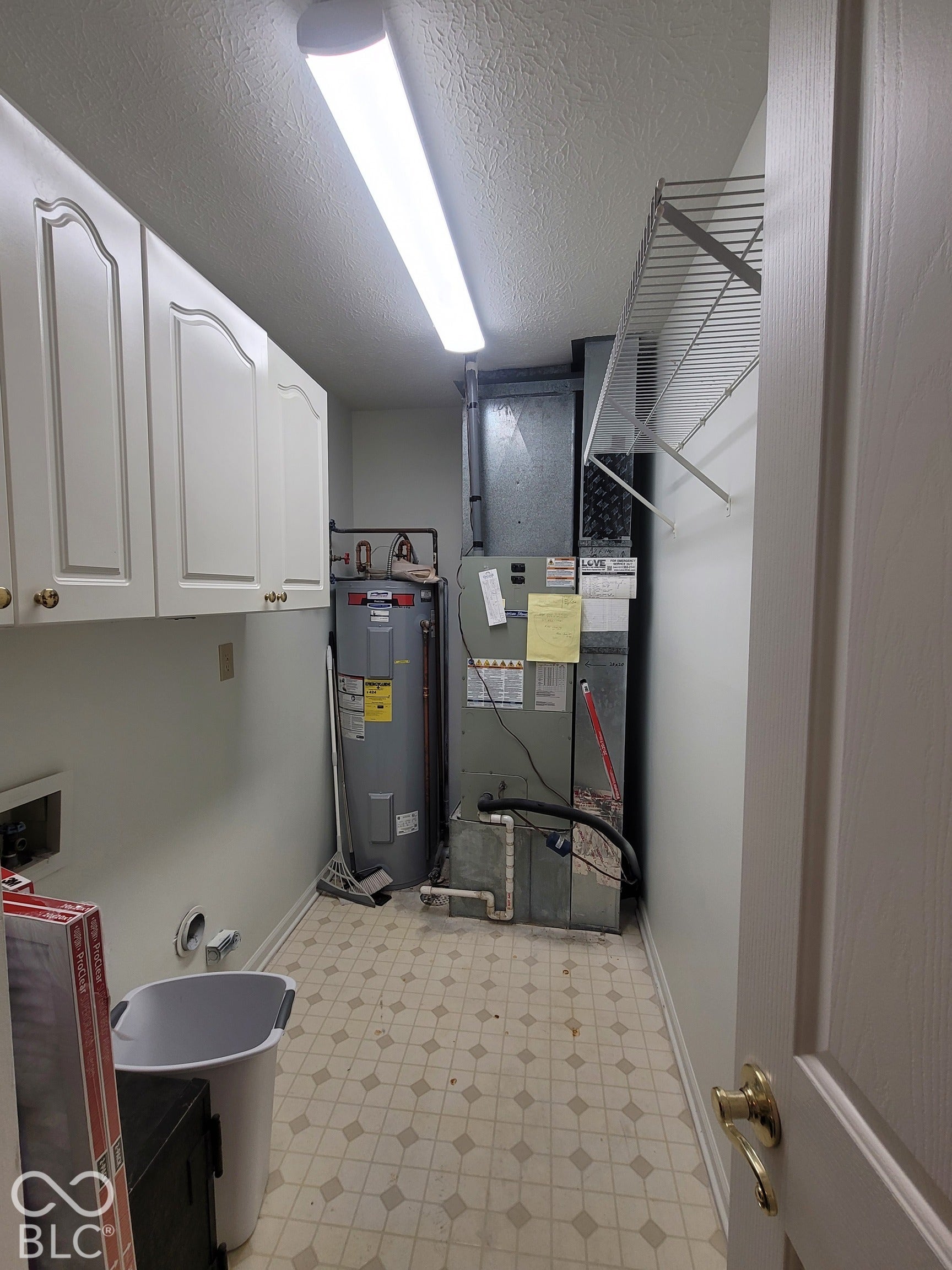 Utility area featuring white raised-panel upper cabinetry, a wire shelving unit, a vertical water heater, and a furnace