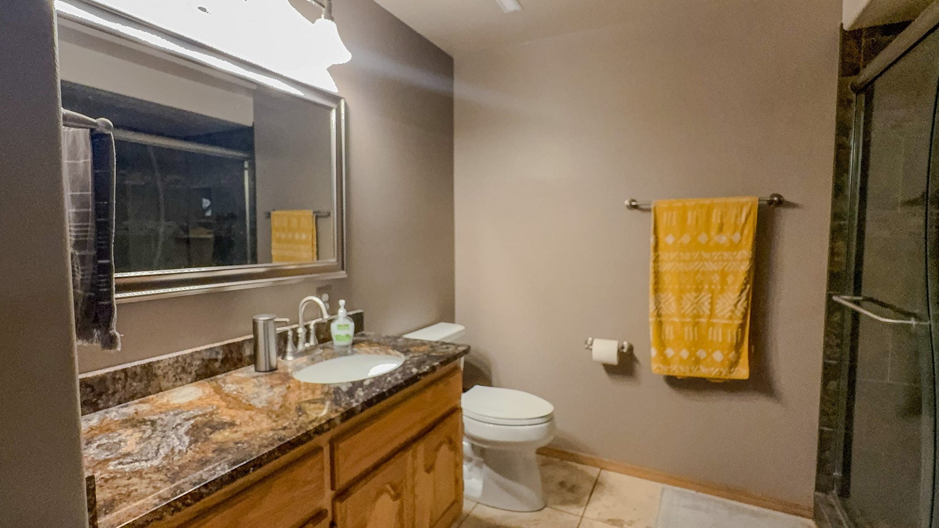 4134 Fox Ridge Drive, Helena, MT 59602 Downstairs Bathroom featuring toilet, vanity, tile patterned flooring, an enclosed shower, and baseboards