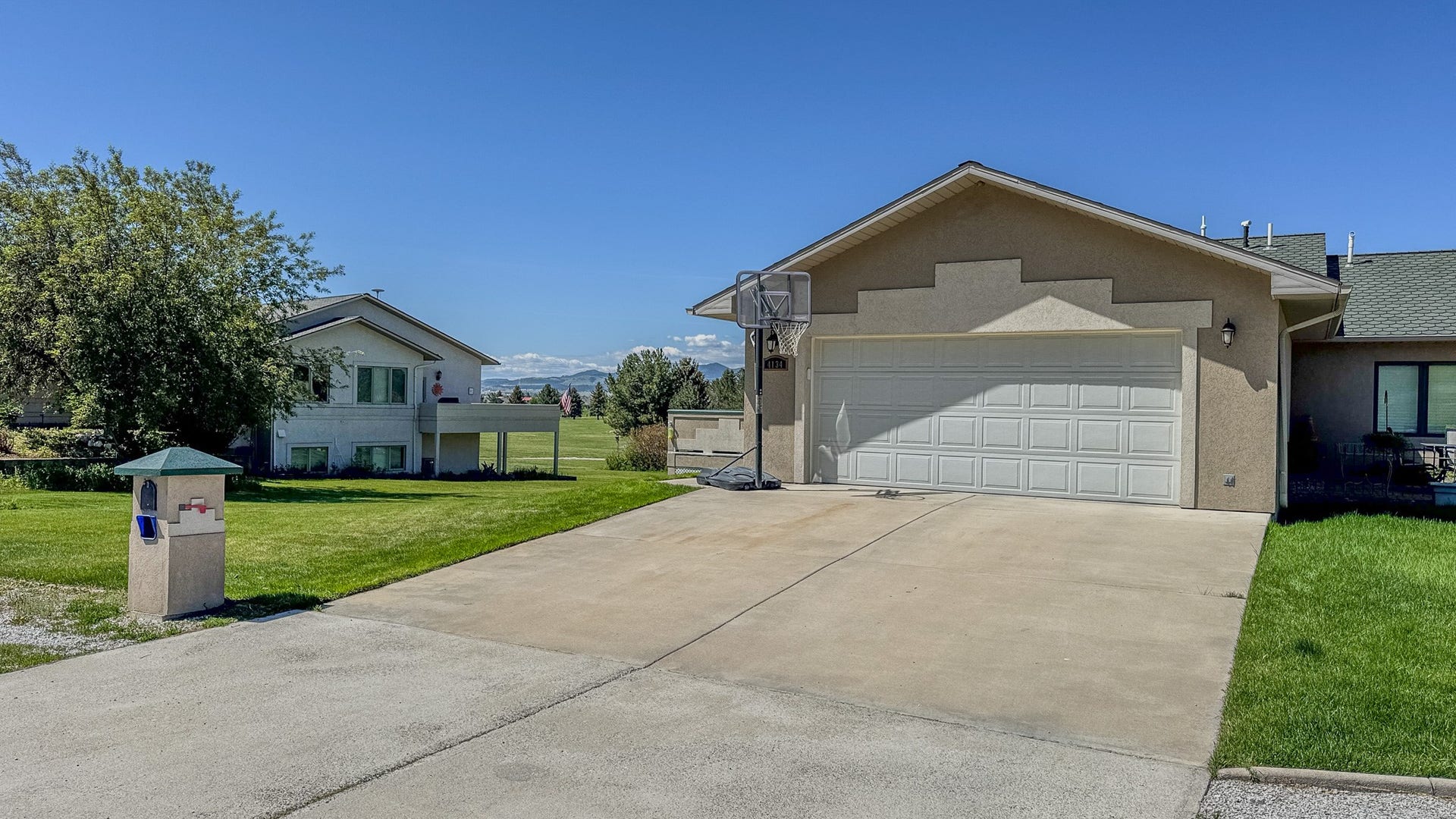 4134 Fox Ridge Drive, Helena, MT 59602 View of front of property featuring a front lawn, stucco siding, concrete driveway, a garage, and a mountain view