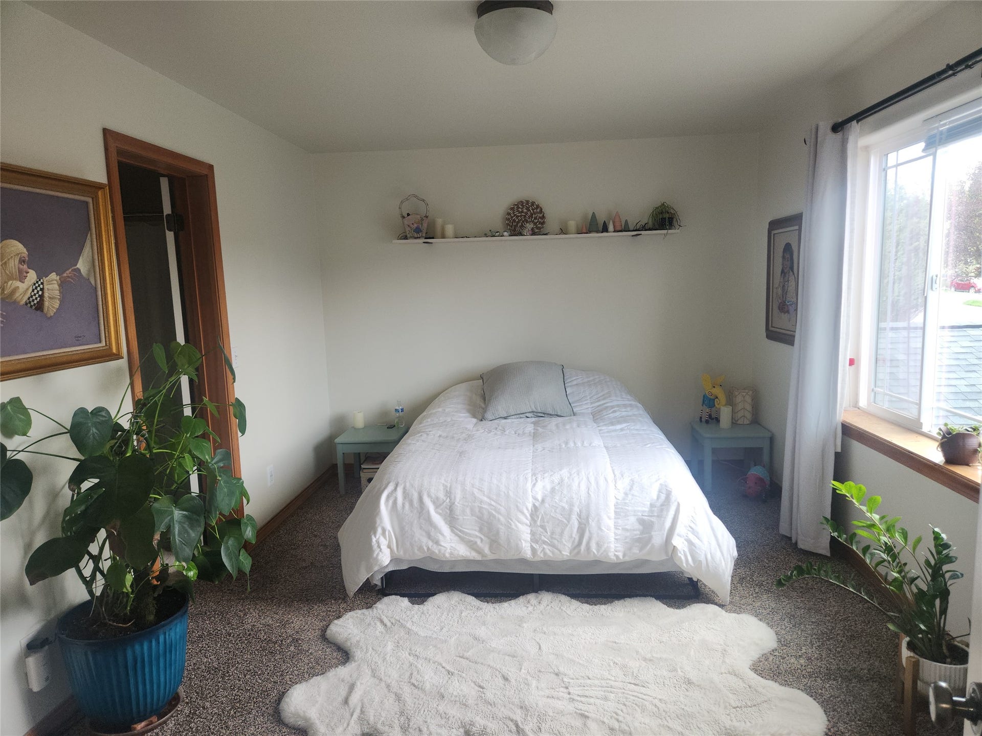 114 Sunrise Terrace, #114, Bigfork, MT 59911 Carpeted bedroom featuring a wood-trimmed doorway, a window with a wood sill, and a wall-mounted shelf