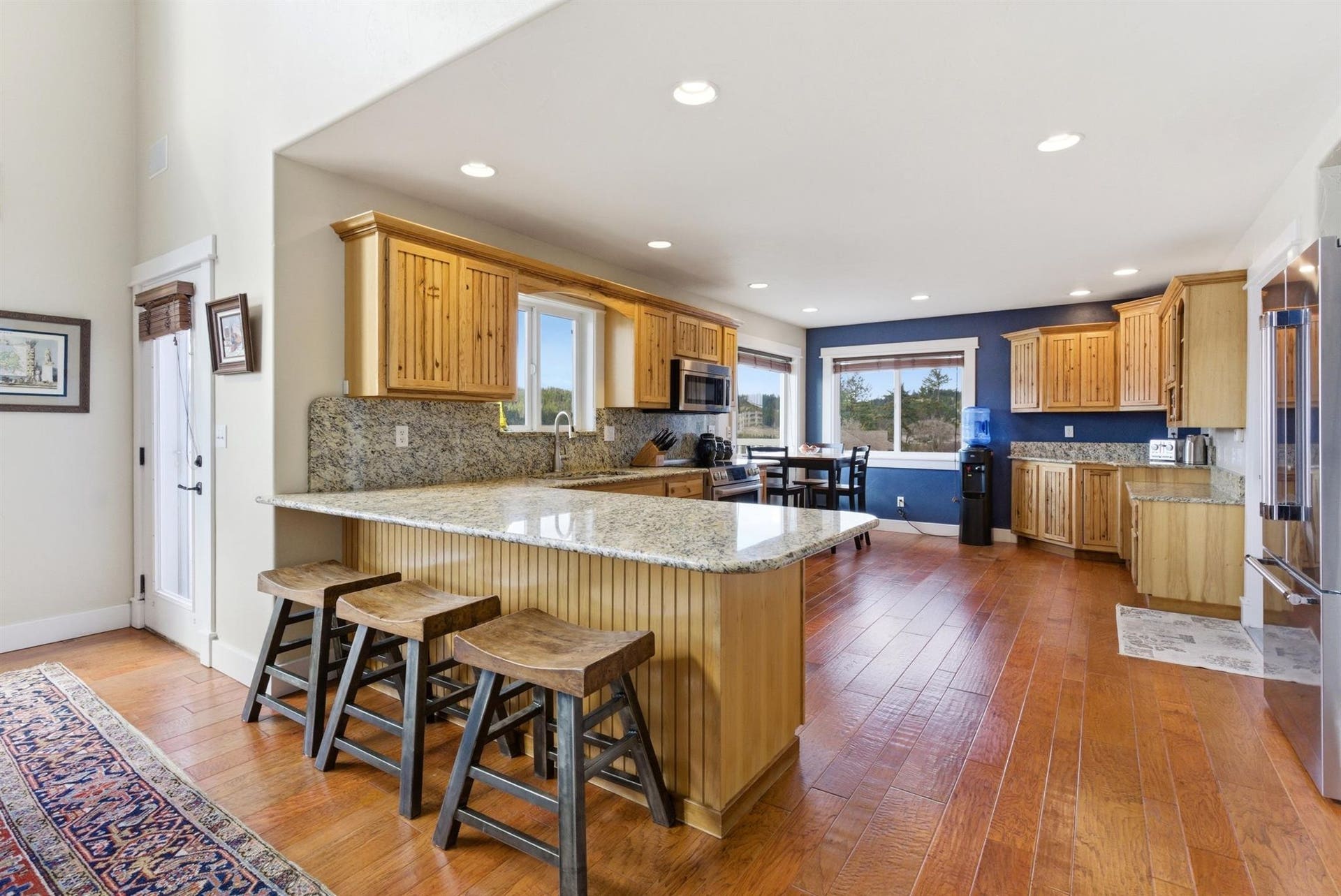 45 Roybals Way, Kalispell, MT 59901 Kitchen featuring a peninsula, a breakfast bar area, light stone countertops, stainless steel appliances, and dark wood-type flooring