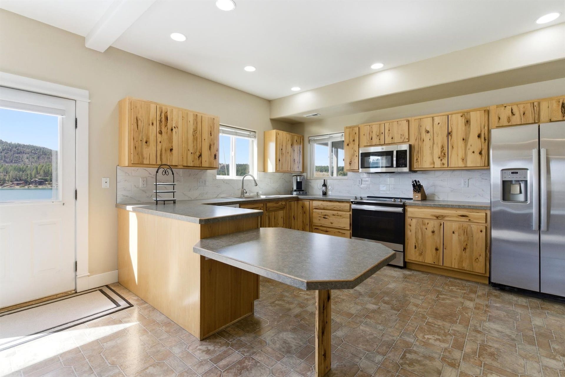 45 Roybals Way, Kalispell, MT 59901 Kitchen featuring a peninsula, stainless steel appliances, a breakfast bar, light wood finish cabinets, and backsplash