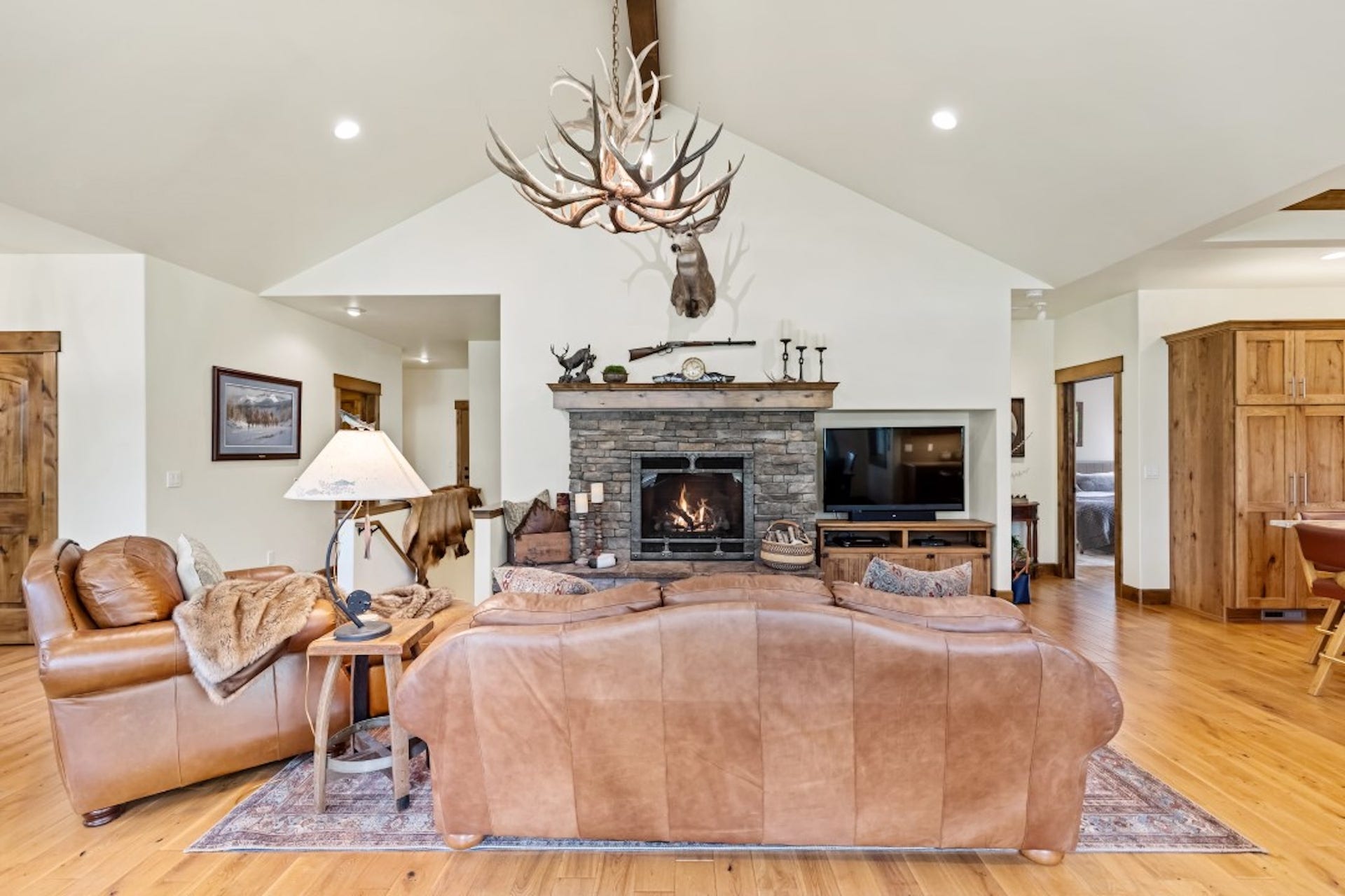 110 Conifer Lane, Bigfork, MT 59911 Living room featuring light wood-style floors, a stone fireplace, a high ceiling, and suspended lighting