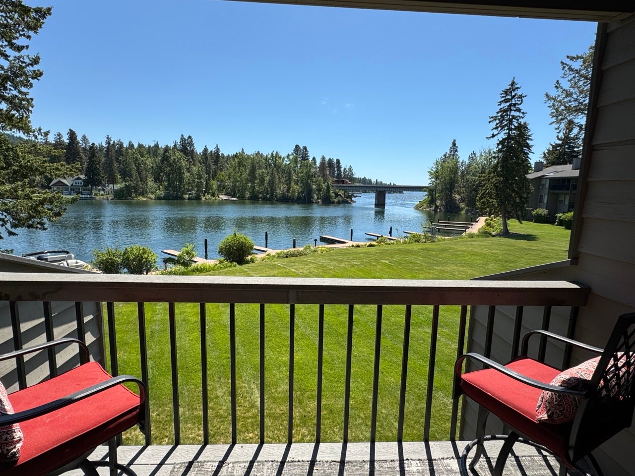 Balcony overlooking a body of water, featuring a wooden railing and a lush green lawn leading to multiple boat docks