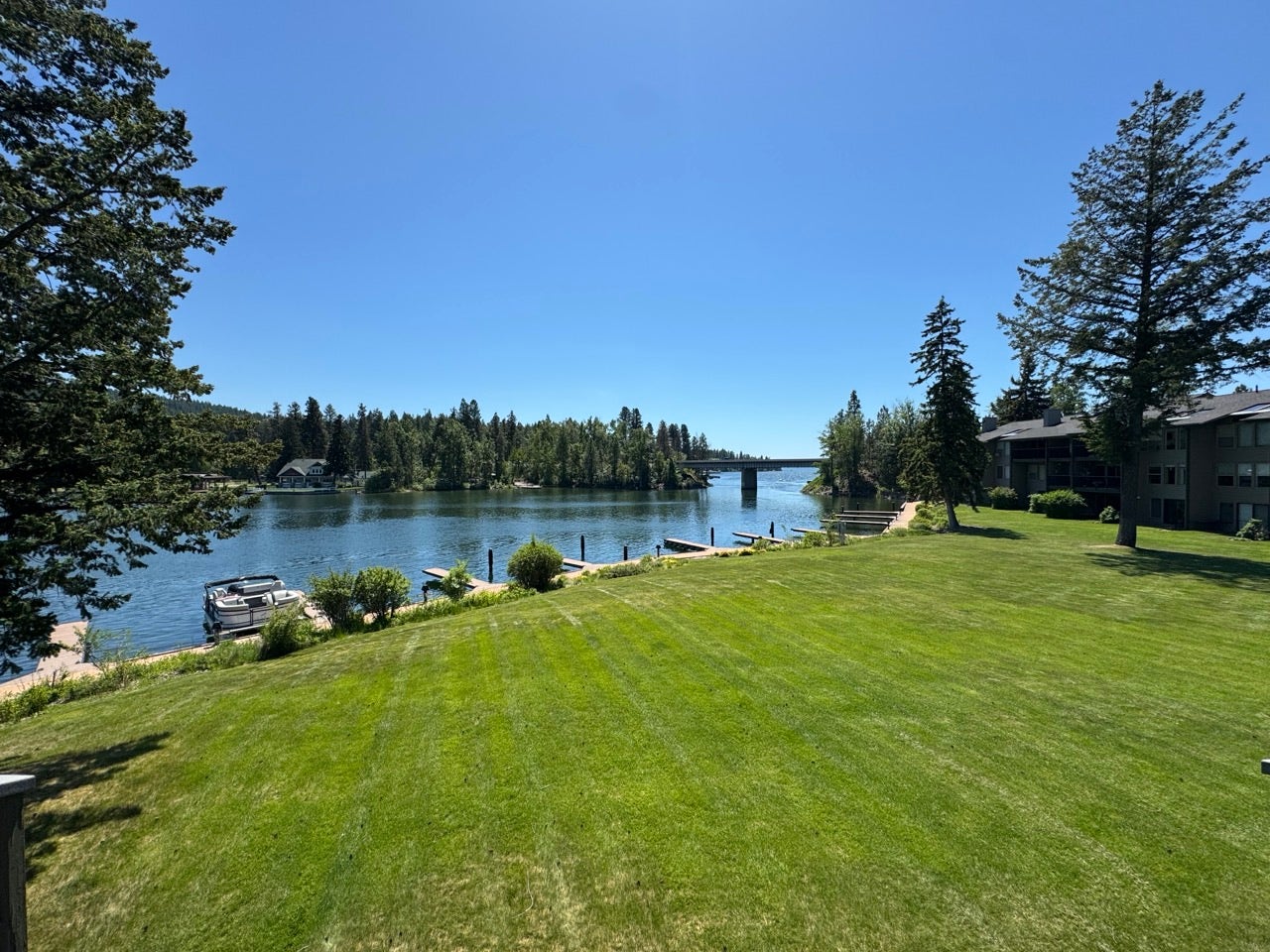 Expansive waterfront lawn featuring mature trees and direct water access