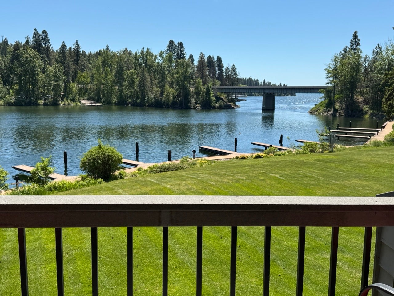 Waterfront property featuring multiple docks, a manicured lawn, and mature trees