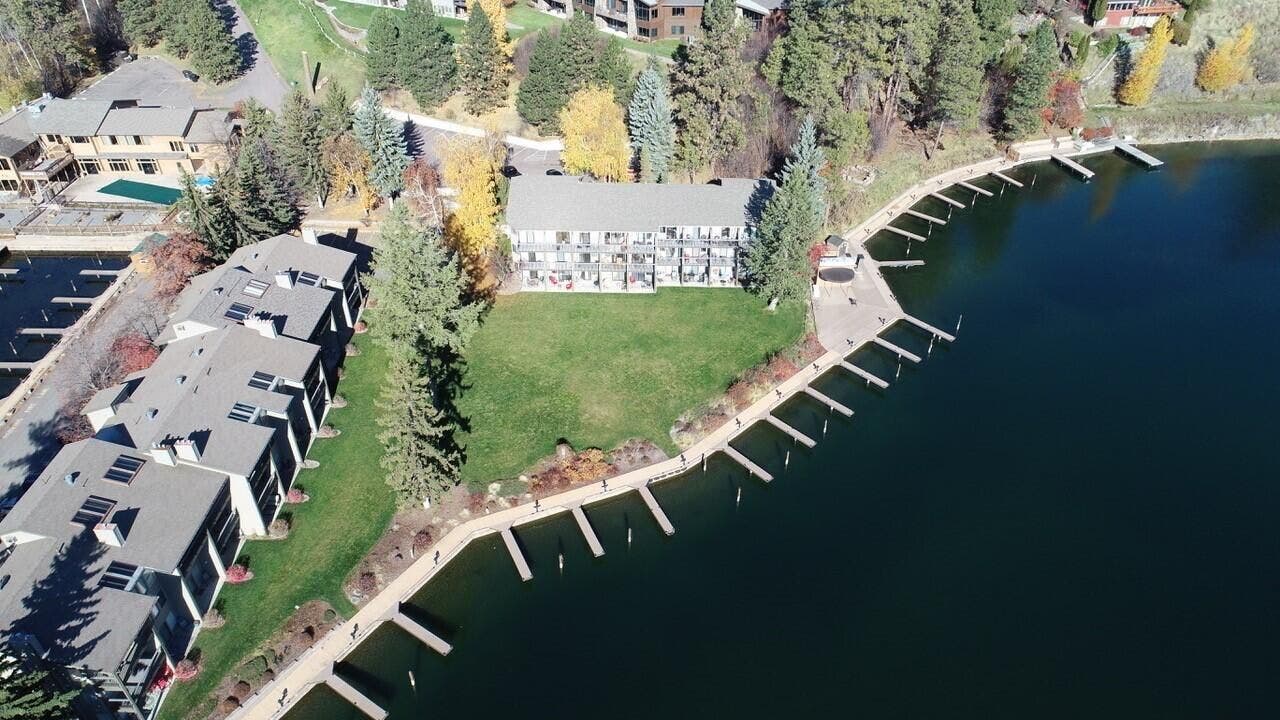 Waterfront property featuring multiple private boat slips, a manicured lawn, and mature evergreen trees