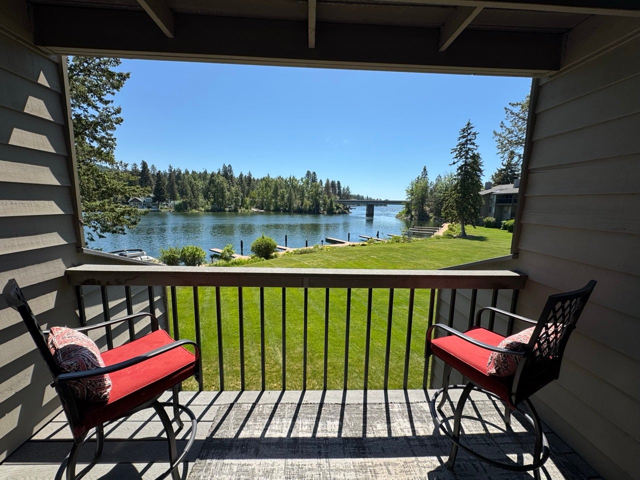 Private balcony with slatted wood-finish flooring, black metal railing, and a waterfront setting