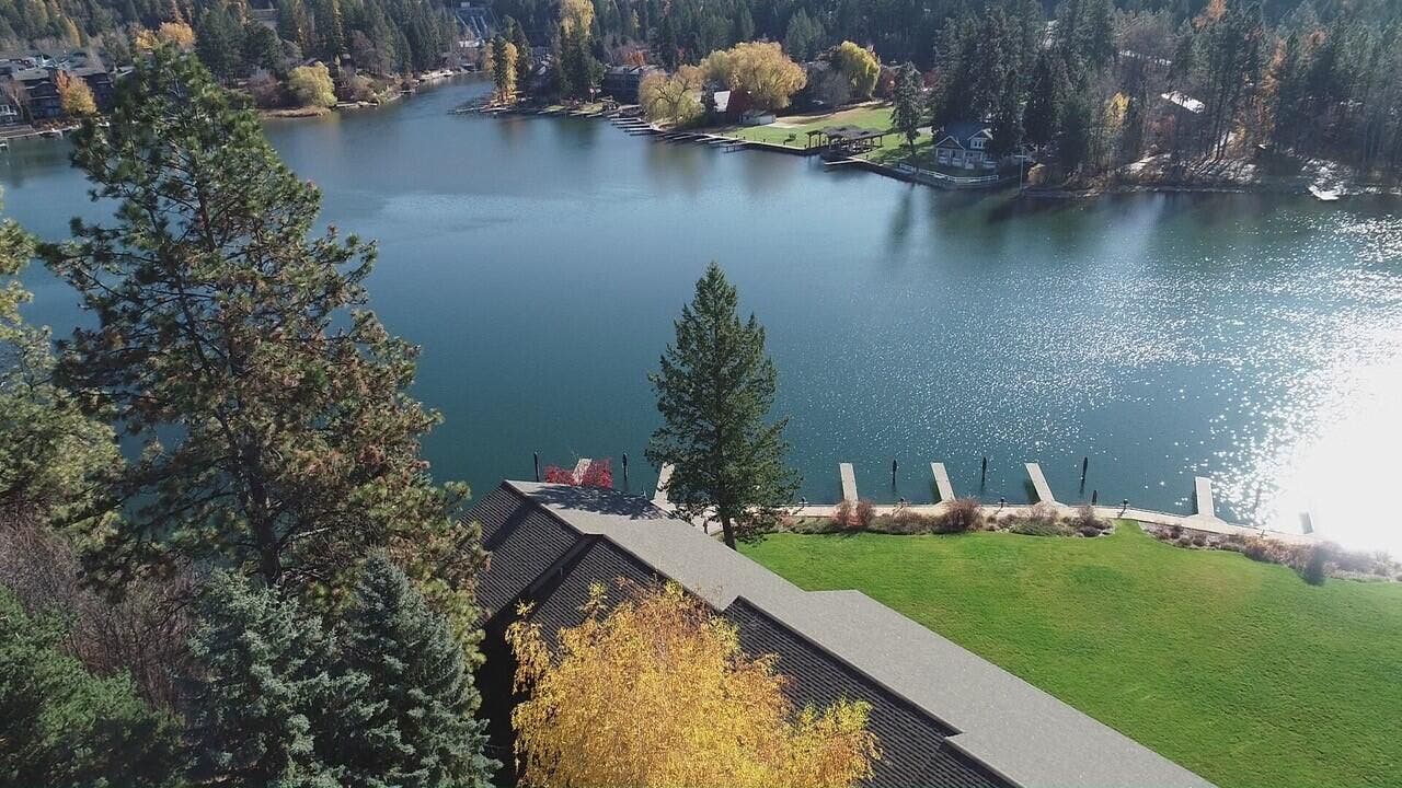 Waterfront property featuring a private lawn area, multiple private docks, and mature trees
