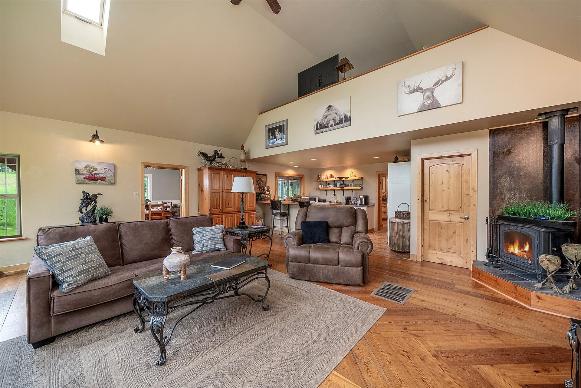 777 Mt Highway 83, Bigfork, MT 59911 Vaulted ceilings with skylight, herringbone wood-finish flooring, and a wood-burning stove with stone surround