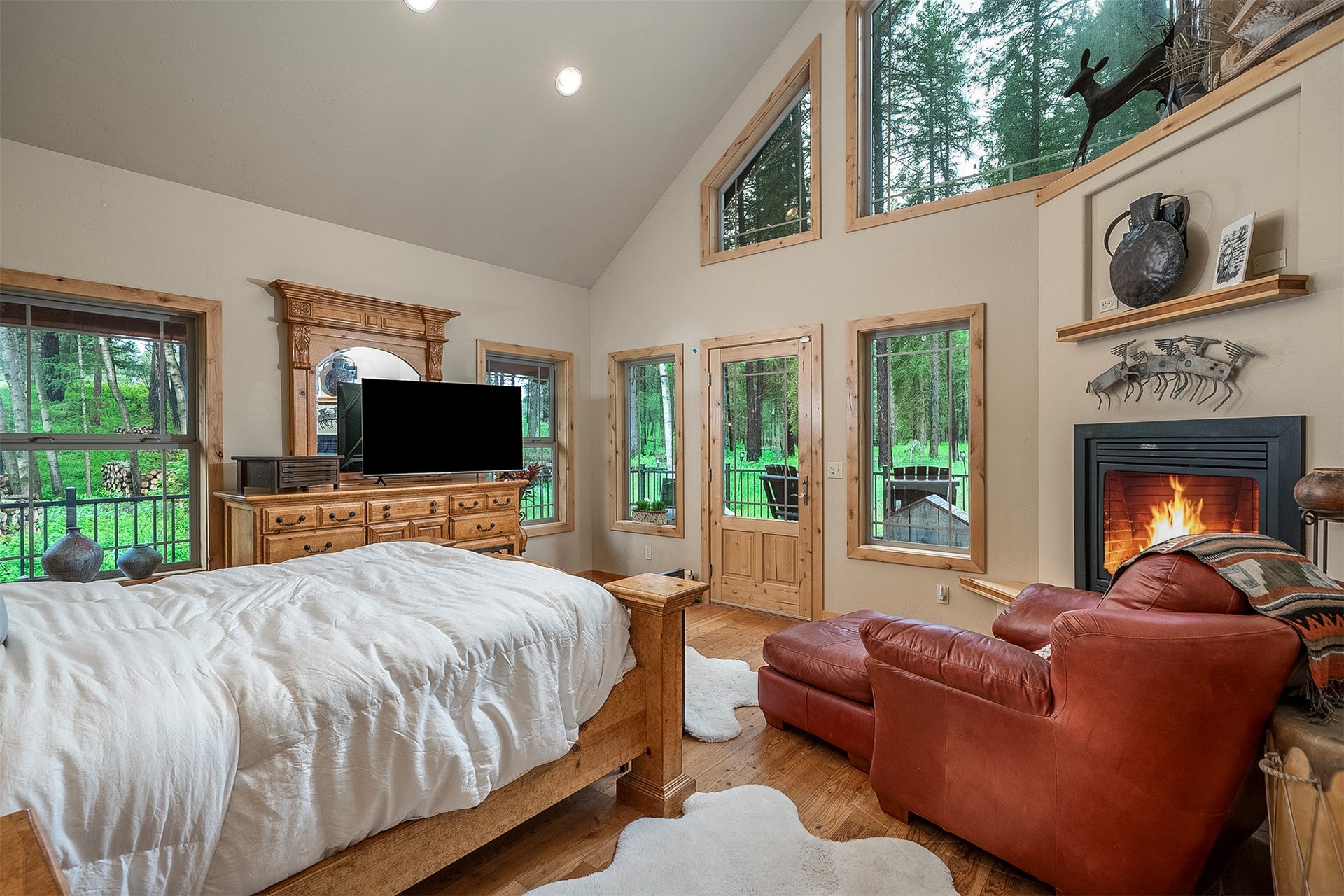 777 Mt Highway 83, Bigfork, MT 59911 Vaulted ceiling with recessed lighting, wood-finish flooring, multiple windows with wood trim, built-in fireplace with black metal surround, and a glass-paneled exterior door