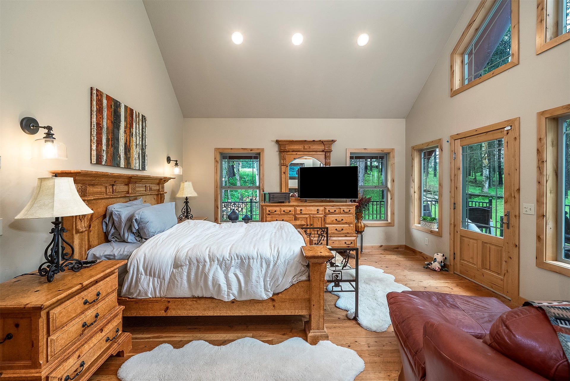 777 Mt Highway 83, Bigfork, MT 59911 Spacious room featuring vaulted ceilings, light wood-finish flooring, recessed lighting, multiple windows with wood trim, and a glass-paneled exterior door