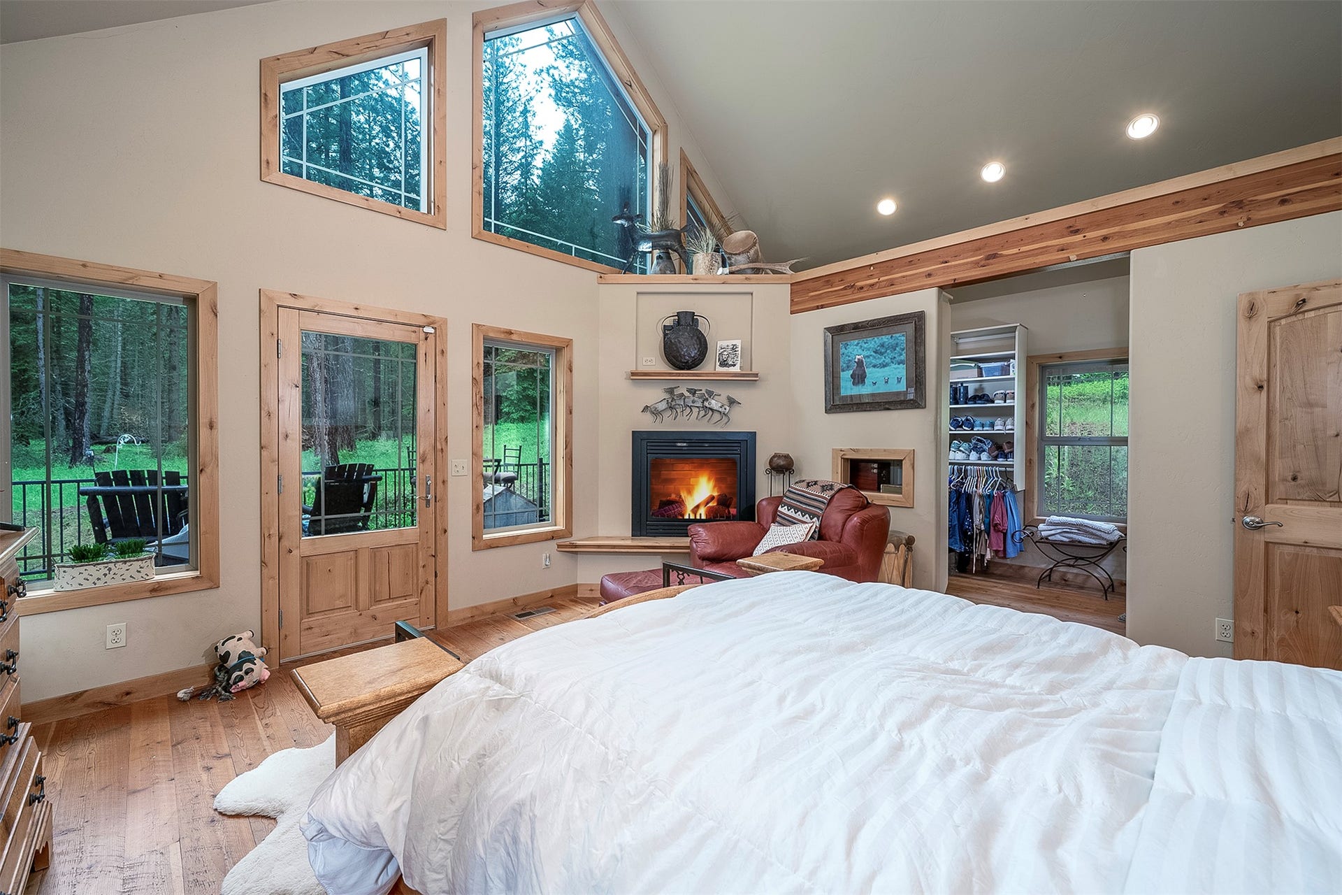 777 Mt Highway 83, Bigfork, MT 59911 Vaulted ceiling interior featuring extensive wood-finish flooring and trim, a corner fireplace, multiple windows, and a glass-paneled door