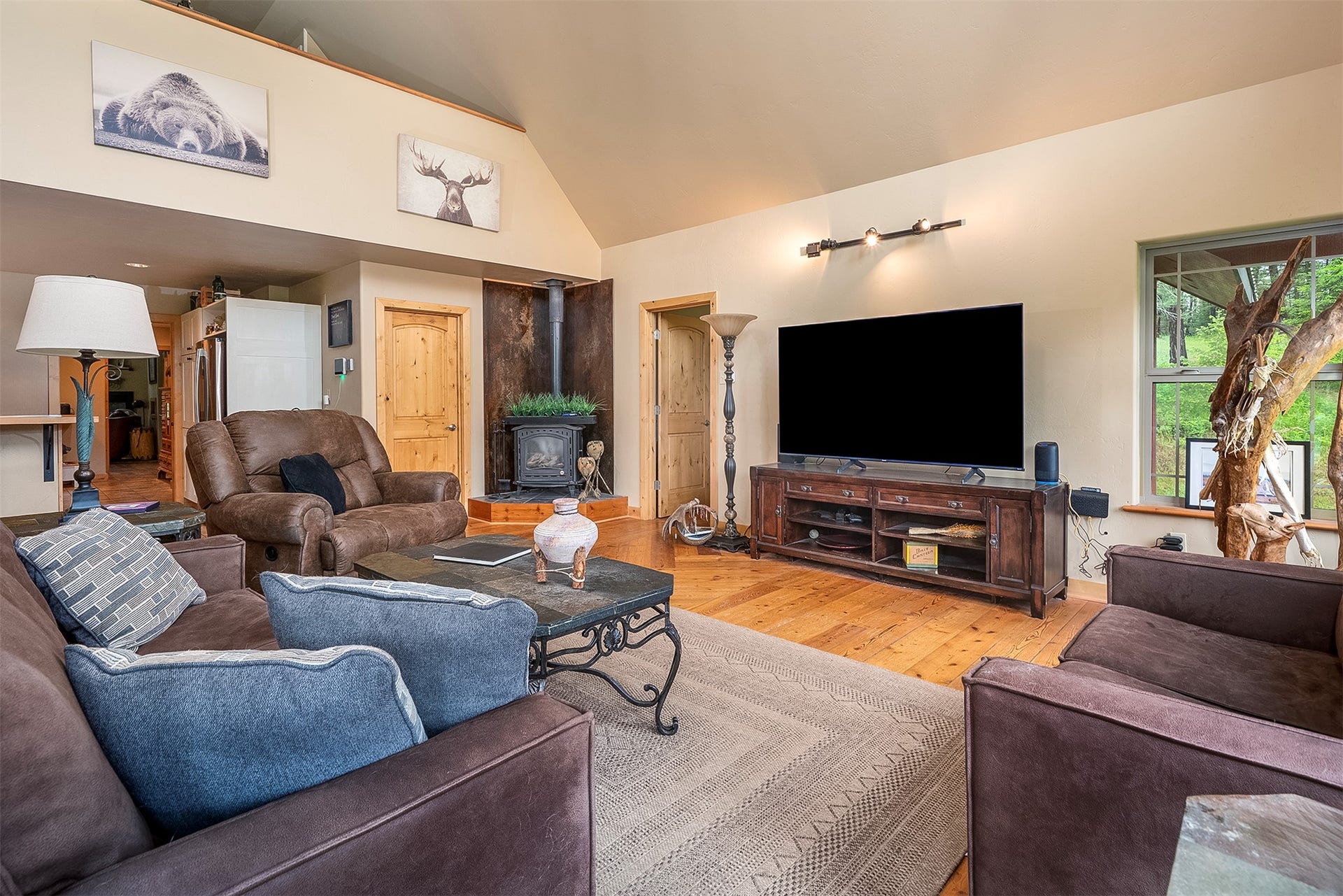 777 Mt Highway 83, Bigfork, MT 59911 Living room featuring vaulted ceilings, wood-finish flooring, a freestanding wood stove, and a window with natural light