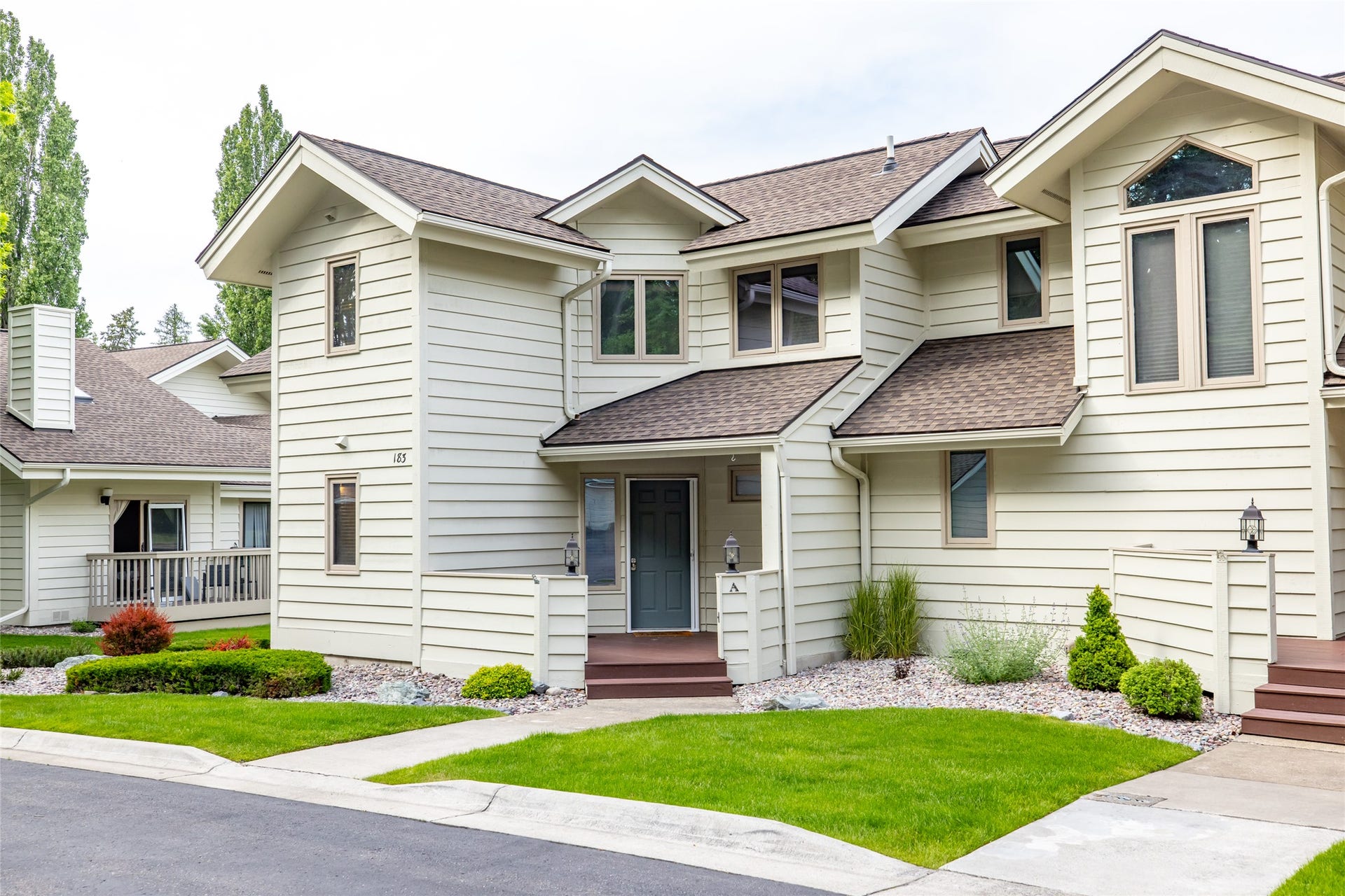 183 Golf Terrace, #A, Bigfork, MT 59911 Multi-level residence featuring light-colored horizontal siding, brown shingle roofing, and multiple gables