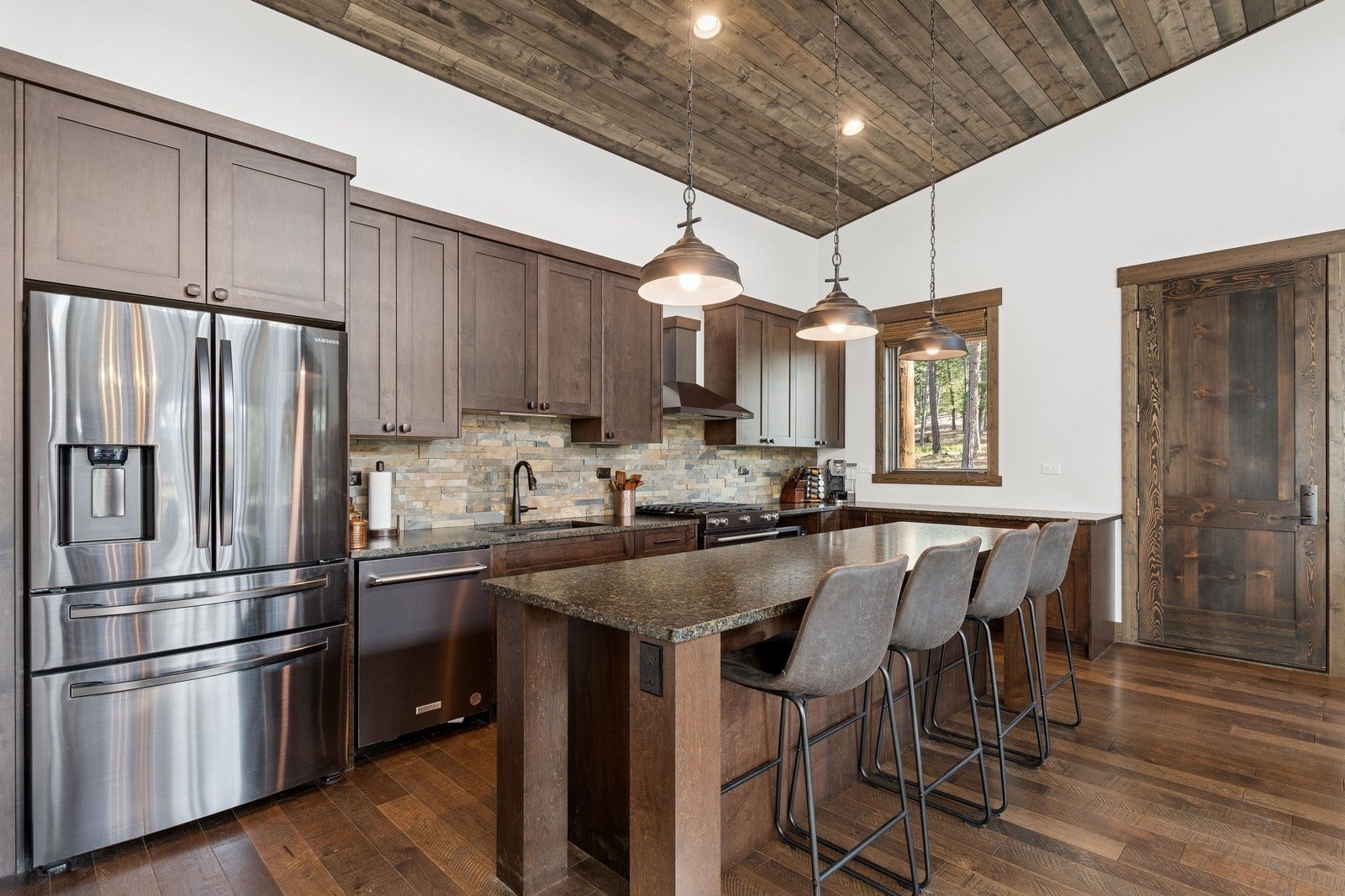 30 Boulder Lane, Eureka, MT 59917 Kitchen with stainless steel appliances, a sink, wood ceiling, wall chimney range hood, and tasteful backsplash