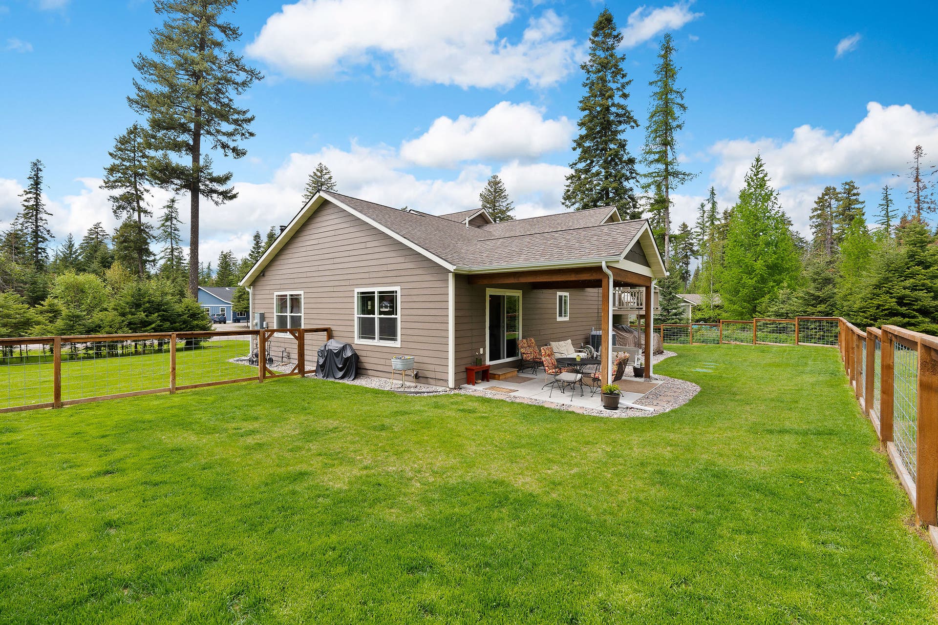 13404 Crescent Moon Drive, Bigfork, MT 59911 Broad view of the expansive backyard showing the covered patio and level lawn