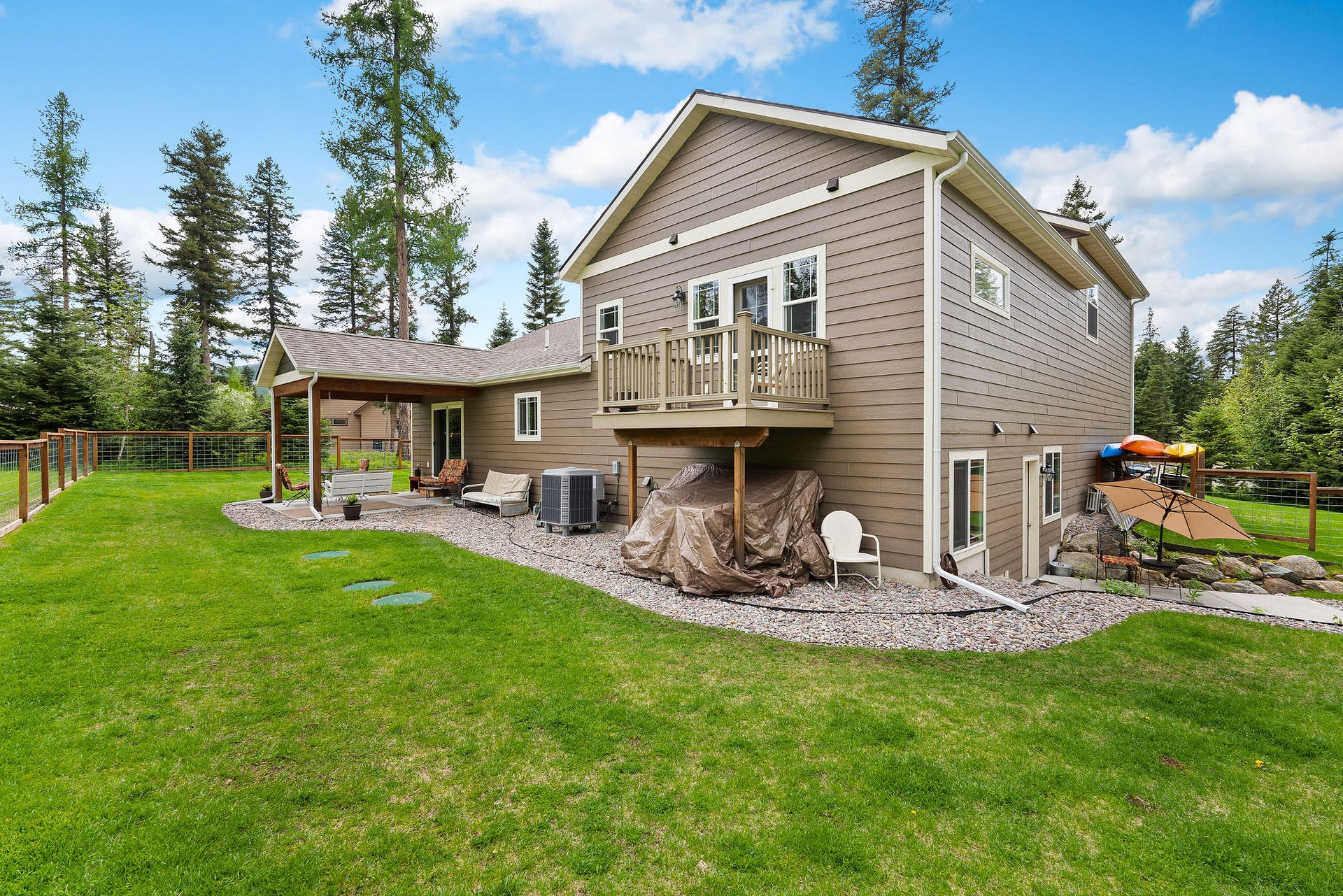 13404 Crescent Moon Drive, Bigfork, MT 59911 Rear exterior overview featuring the upper primary suite balcony and lower walkout