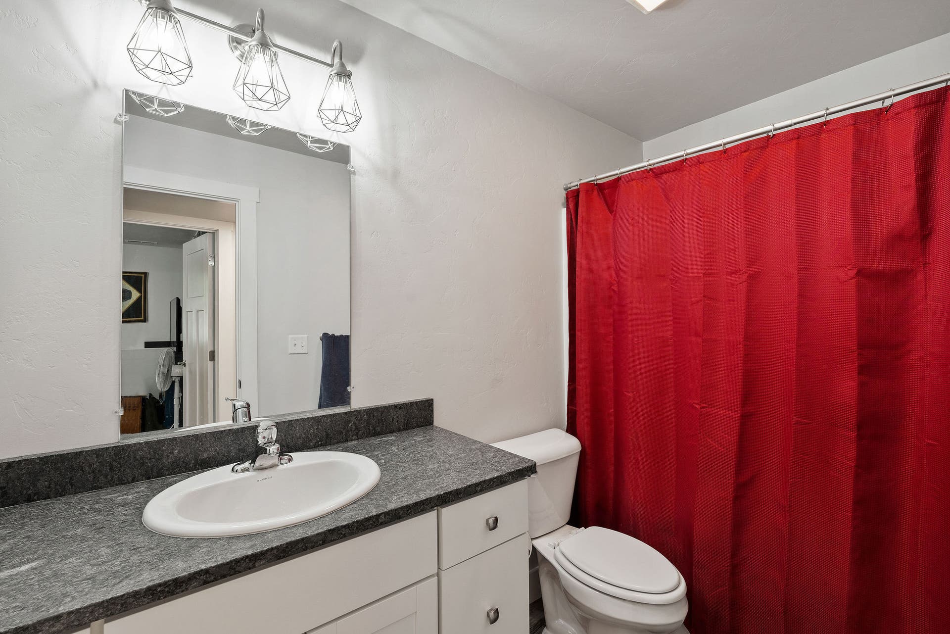 13404 Crescent Moon Drive, Bigfork, MT 59911 Lower-level full bathroom featuring clean white cabinetry and a modern multi-bulb light fixture
