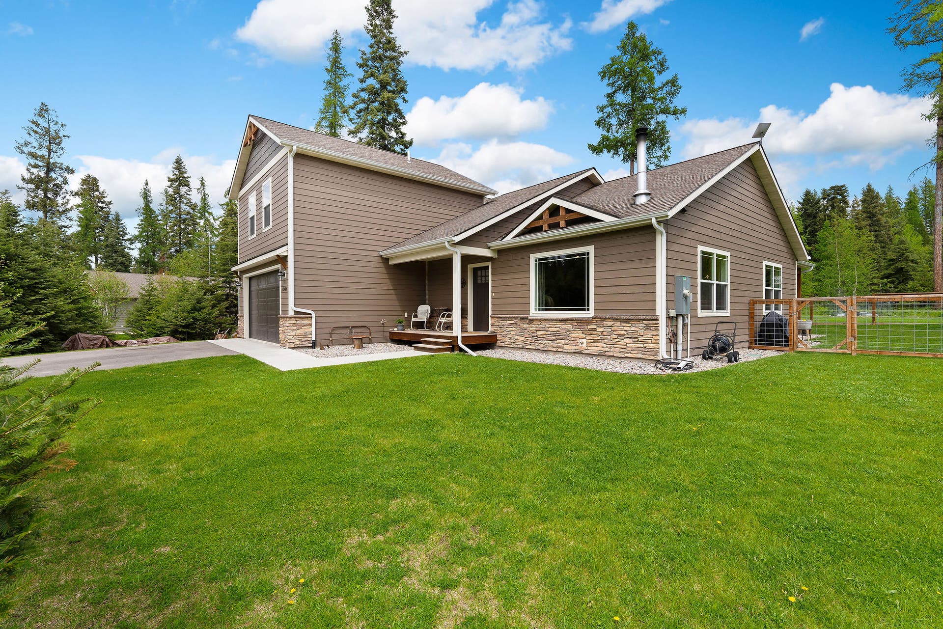13404 Crescent Moon Drive, Bigfork, MT 59911 Side view of the home showing the level front lawn and tree-lined perimeter