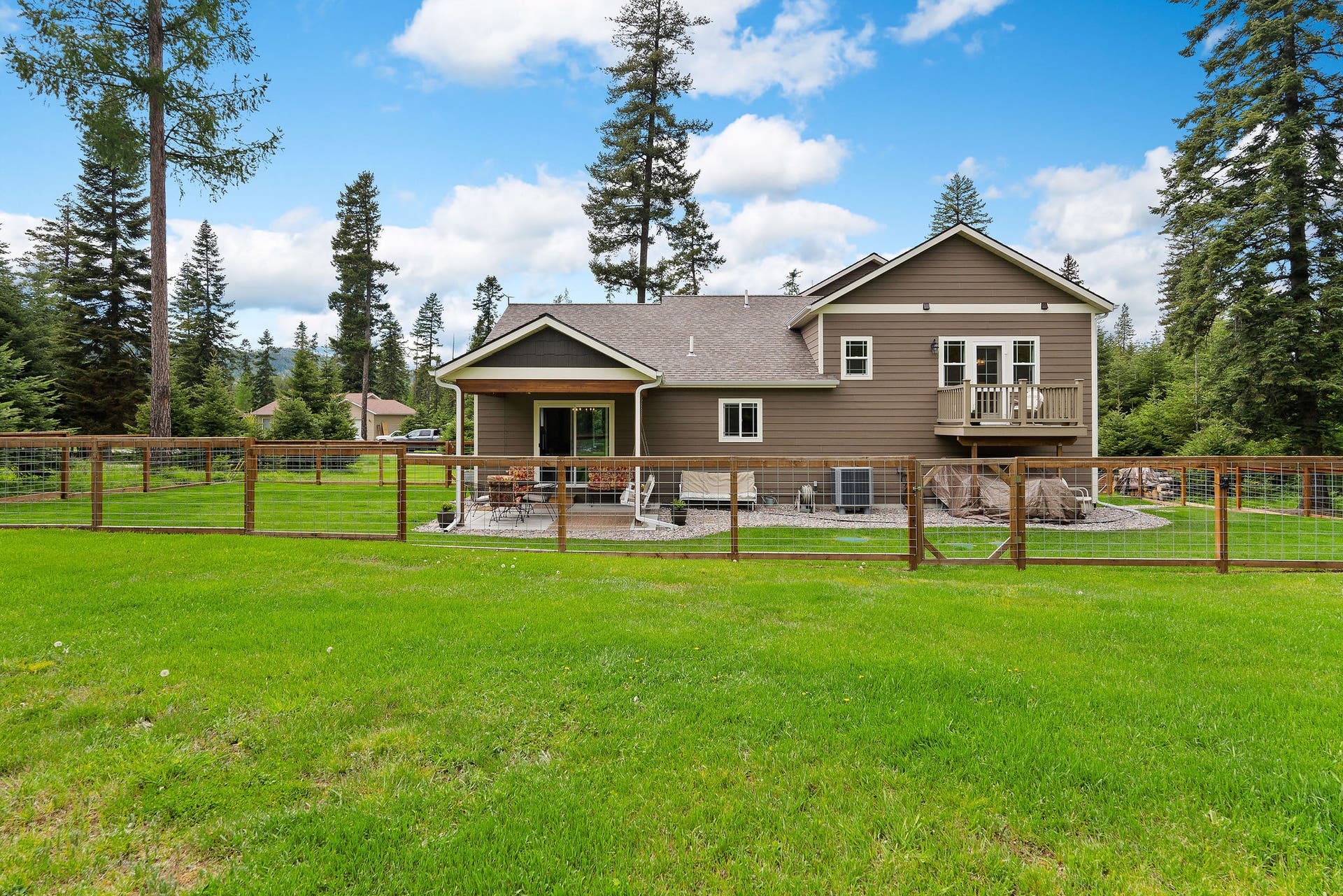 13404 Crescent Moon Drive, Bigfork, MT 59911 Full view of the fully fenced back lawn and modern exterior