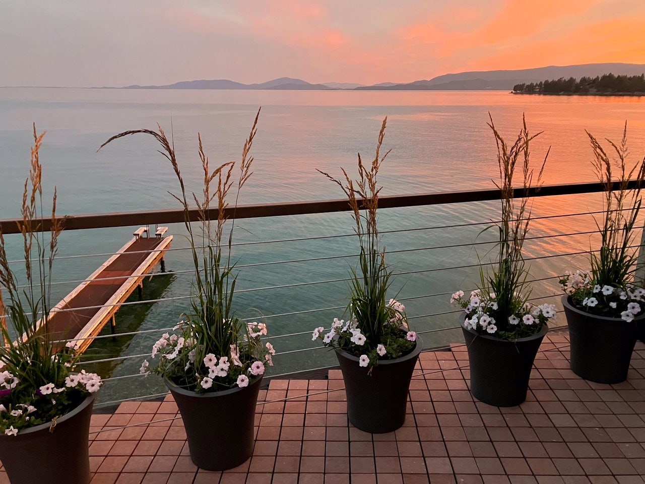 15335 MT Highway 35, Bigfork, MT 59911 Waterfront deck with a wood plank railing, cable balusters, and a visible private dock extending into the water