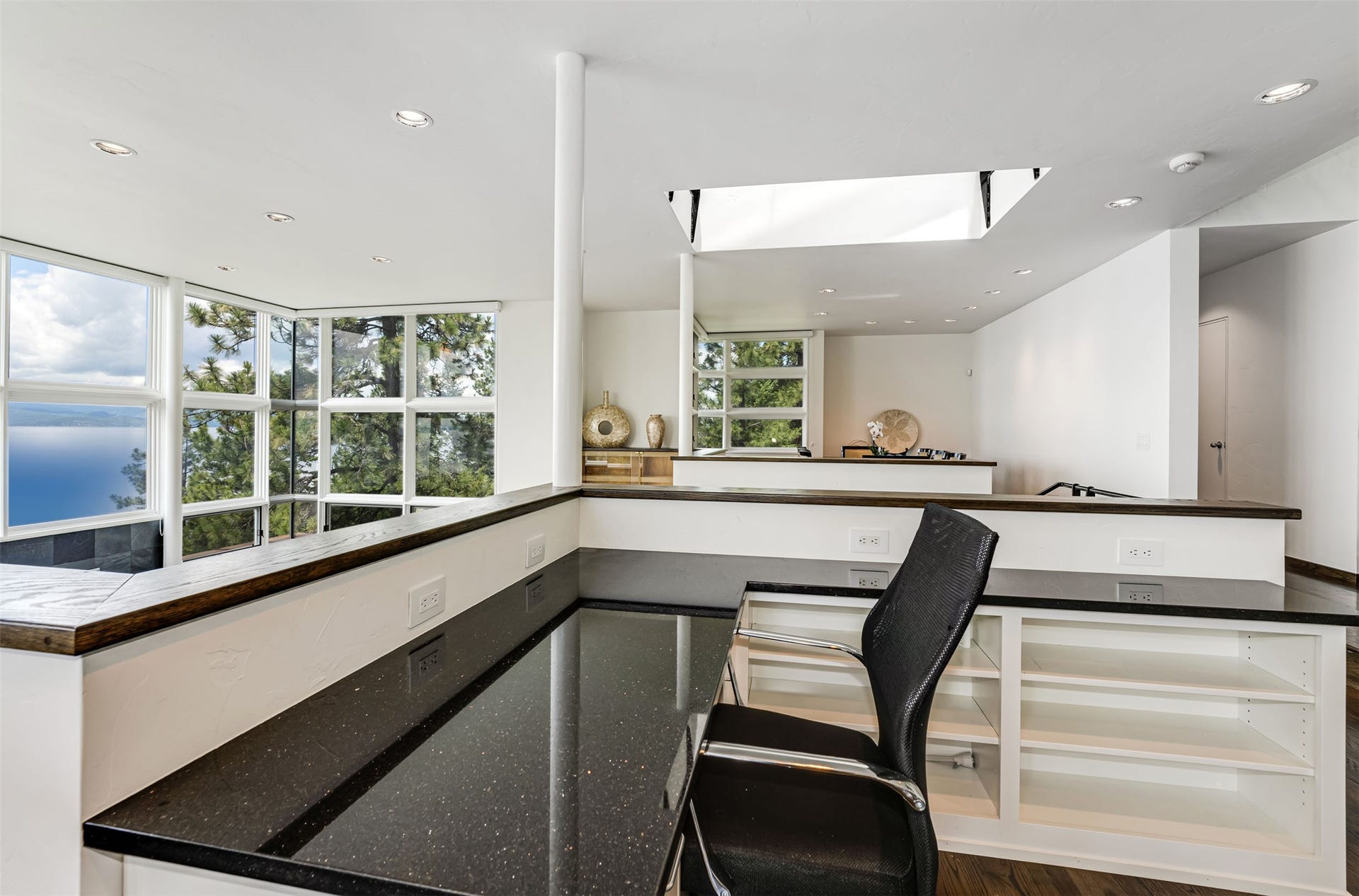 Kitchen office space with bronze flecked granite countertop, integrated shelving, and recessed lighting. Living room beyond.