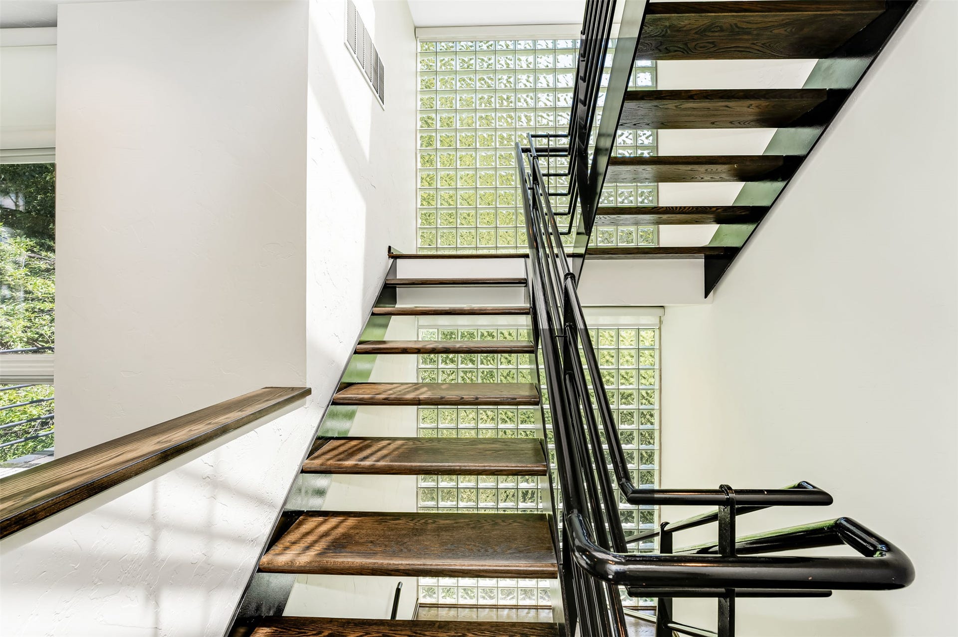 Wood-finish floating staircase with an open riser design and black steel railings
