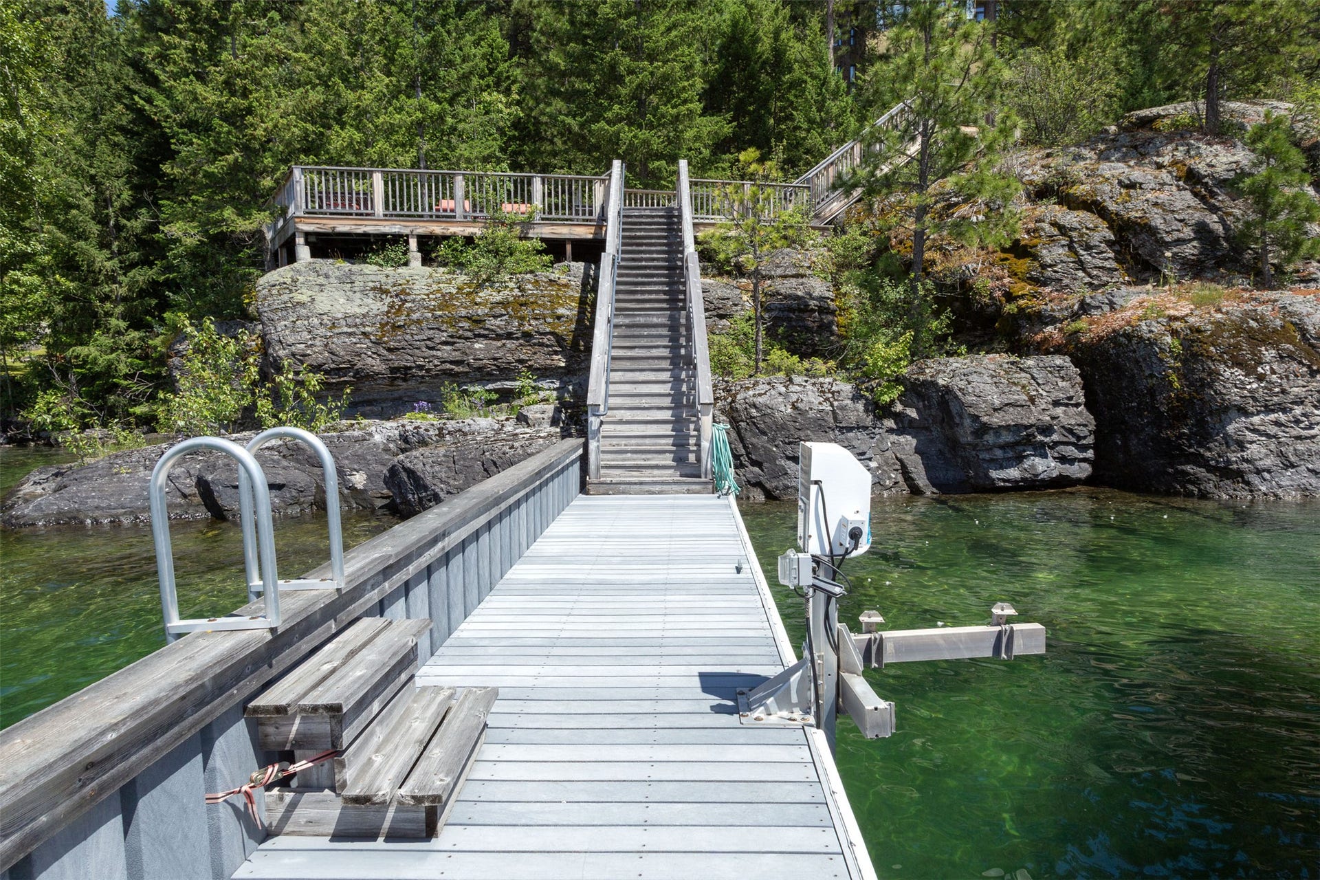 Waterfront property featuring an extensive dock system with integrated seating, a swimming ladder, and a boat lift