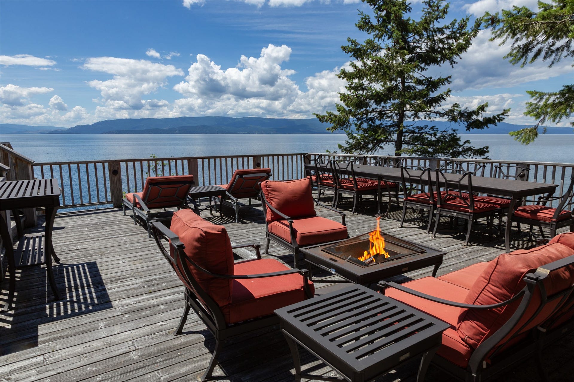 Expansive wood-finish deck with a metal railing overlooking Flathead Lake and distant mountains