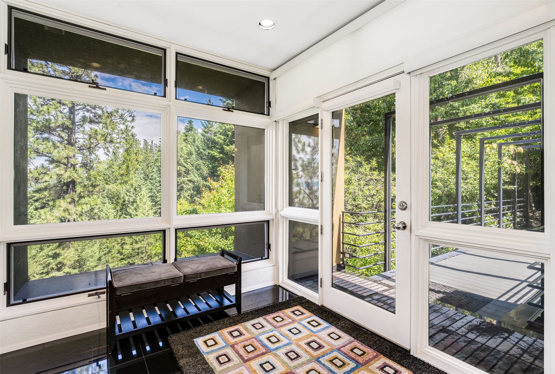 Doubling as a Sunroom, floor-to-ceiling windows and a full-light glass door provide abundant natural light while teasing views of Flathead Lake beyond.