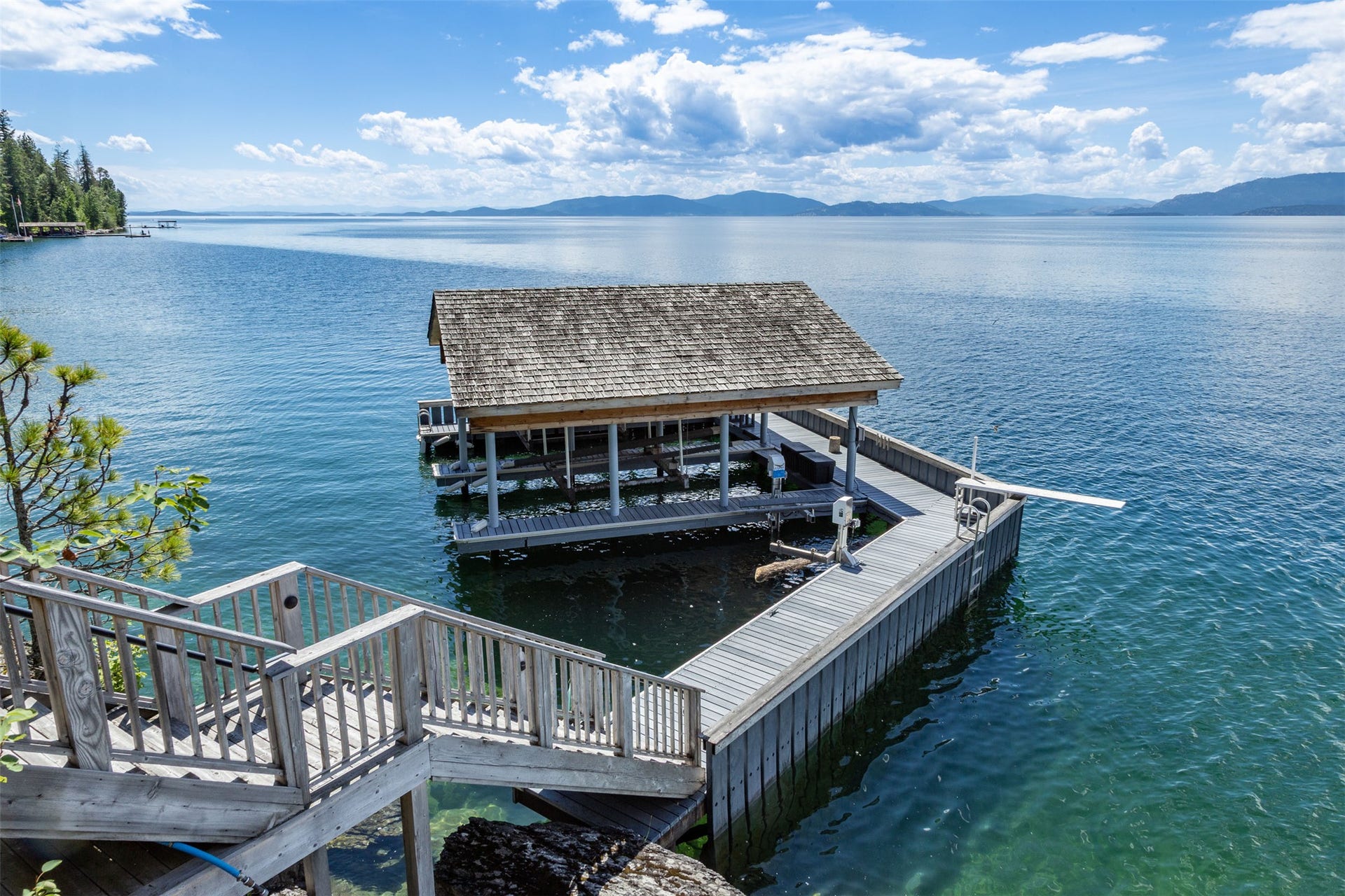 Private dock featuring two covered boat slips, docks, and a diving board.