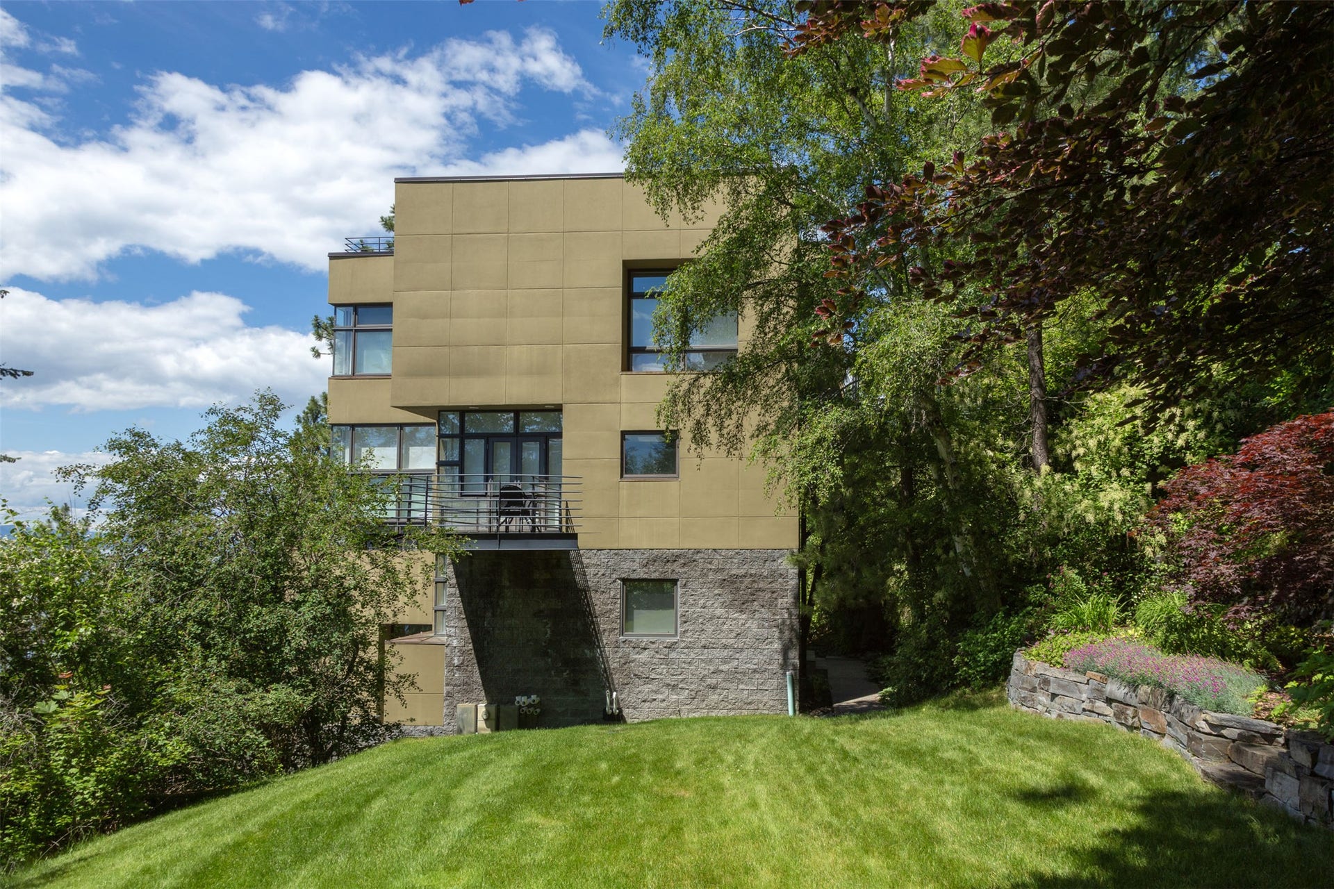 Modern masonry and stucco exterior featuring a prominent balcony porch with forged iron railings. South side of home.